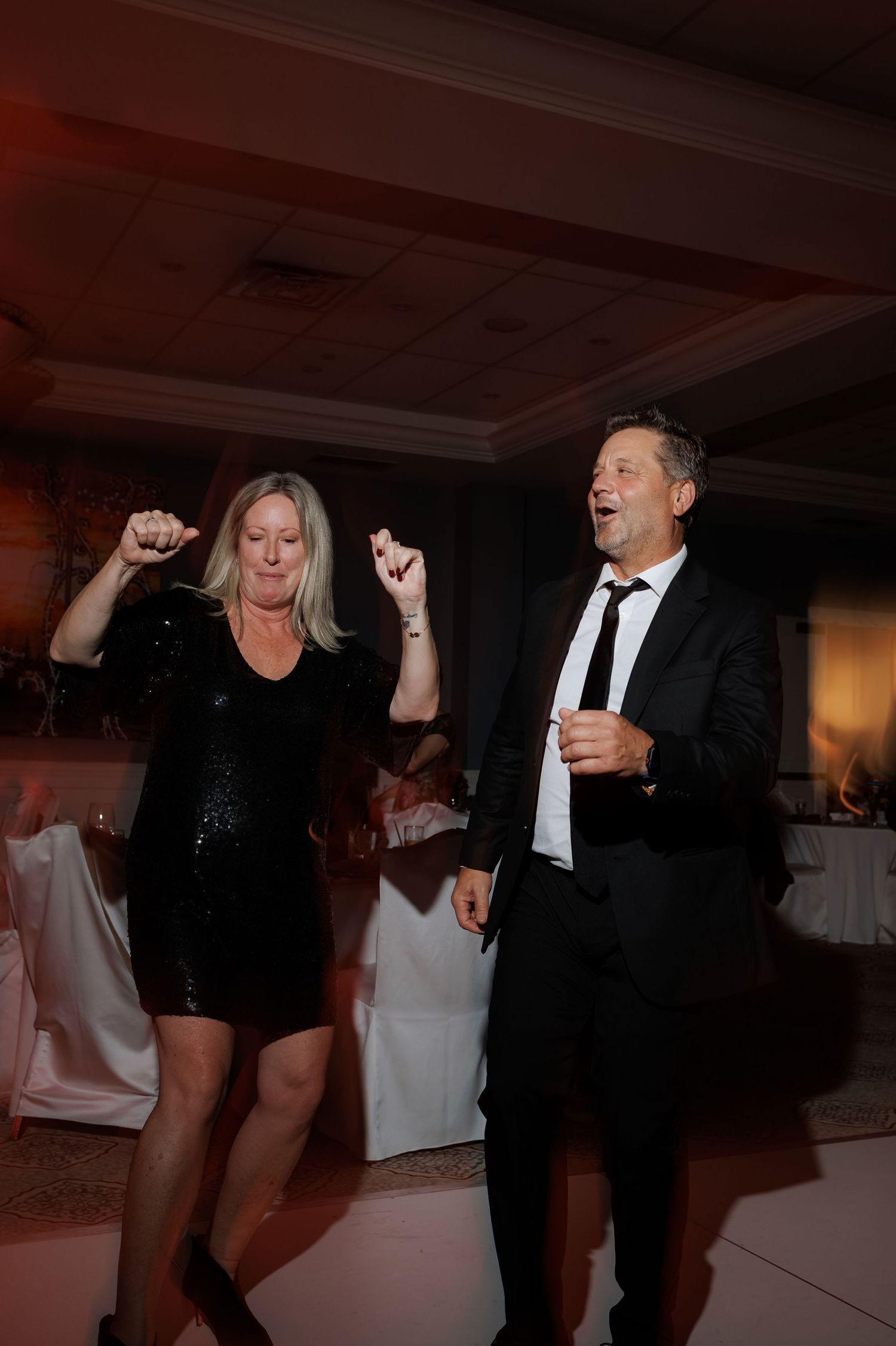 Wedding guests dancing and celebrating on a dimly lit dance floor.