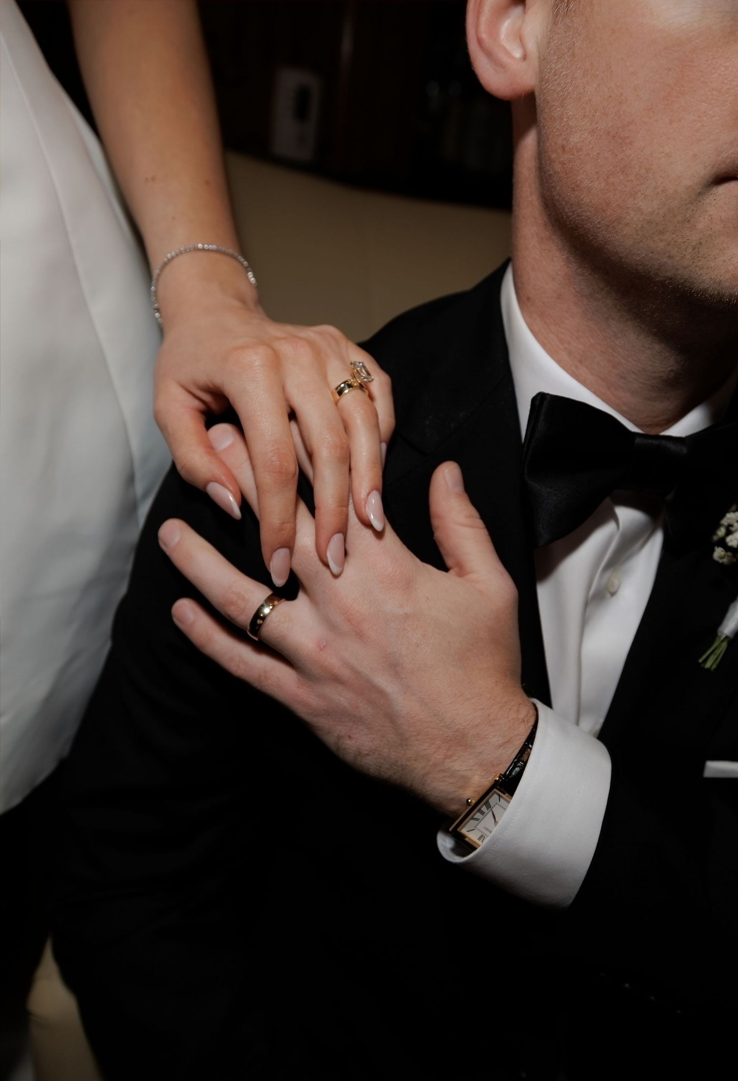 Bride and groom exchange wedding rings, showcasing gold bands and elegant formal attire.