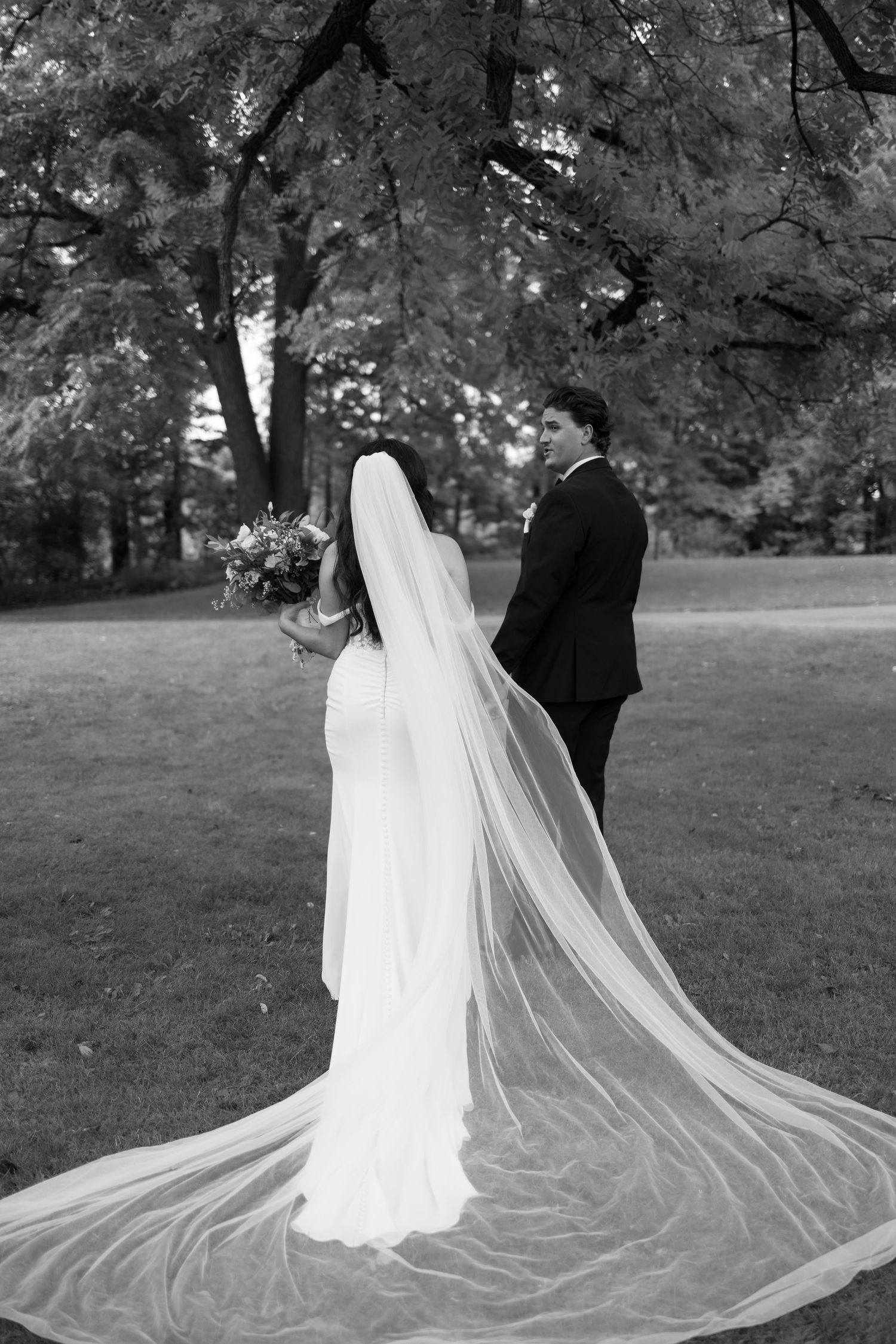 Dramatic black and white photos showcasing a cathedral-length veil flowing in an outdoor setting.