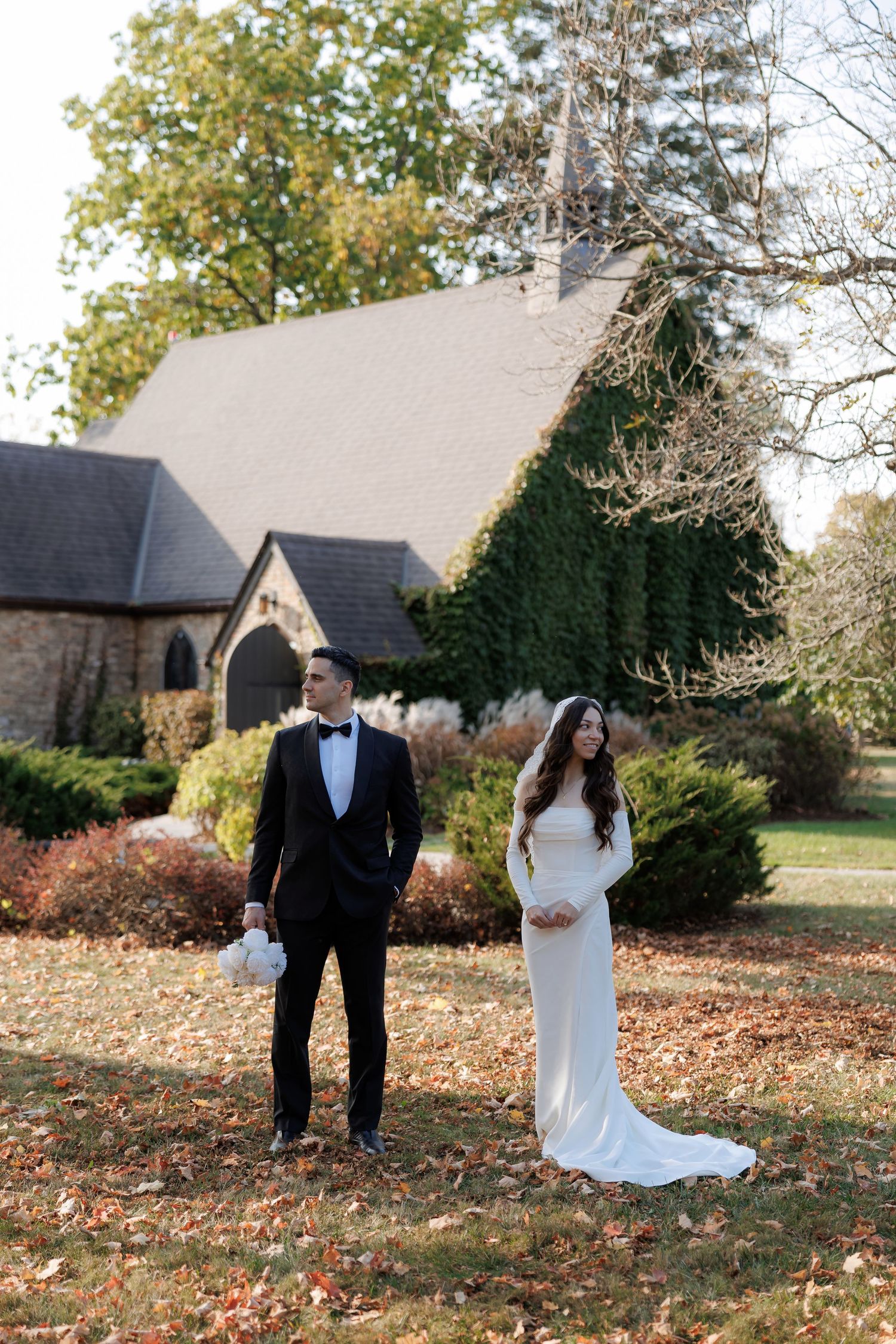 Wedding couple poses in various romantic stances on autumn grounds with stone buildings in background.