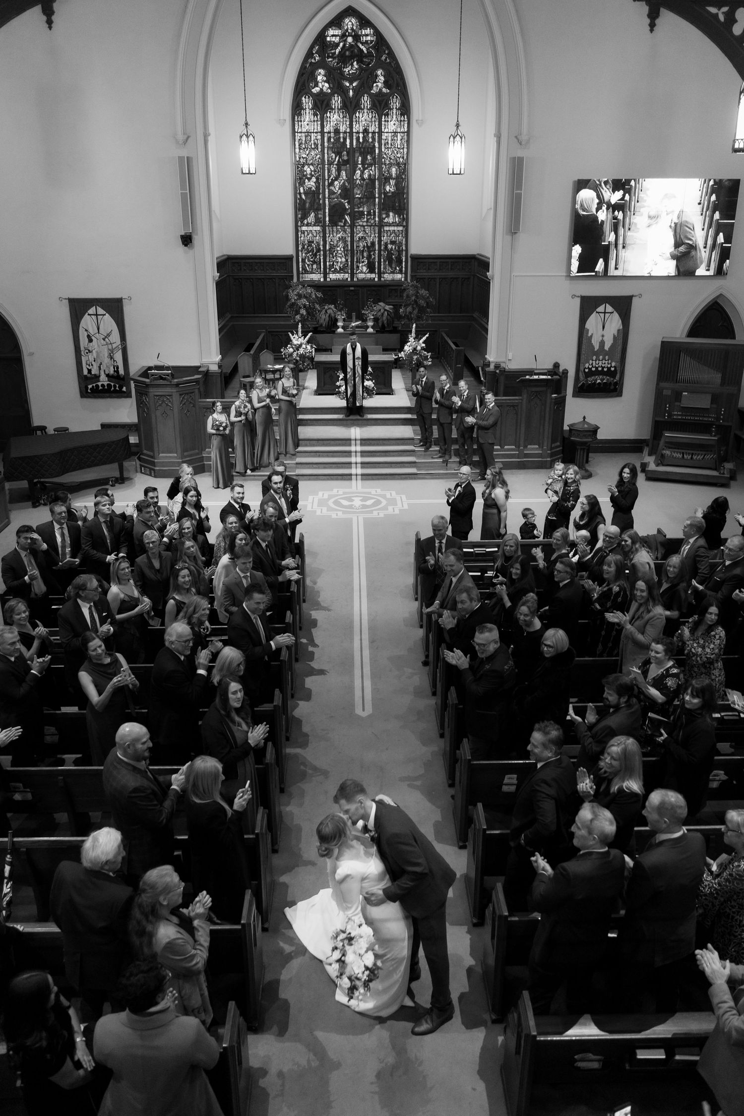 Overhead view of wedding ceremony in church sanctuary filled with guests.