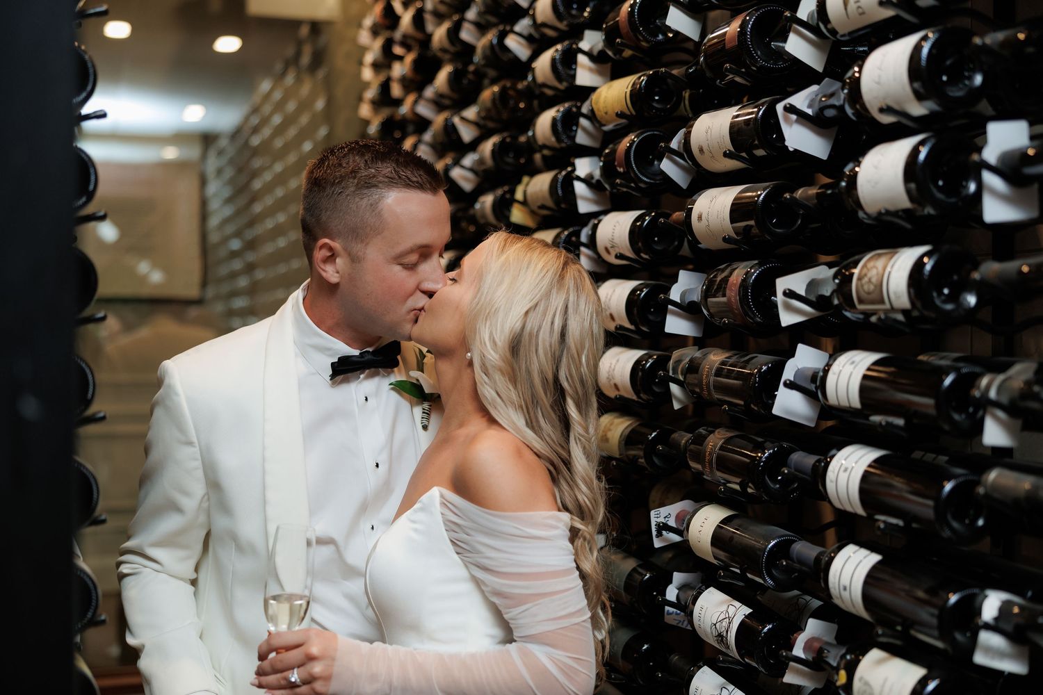 Romantic moment in a wine cellar with racks of bottles in the background.