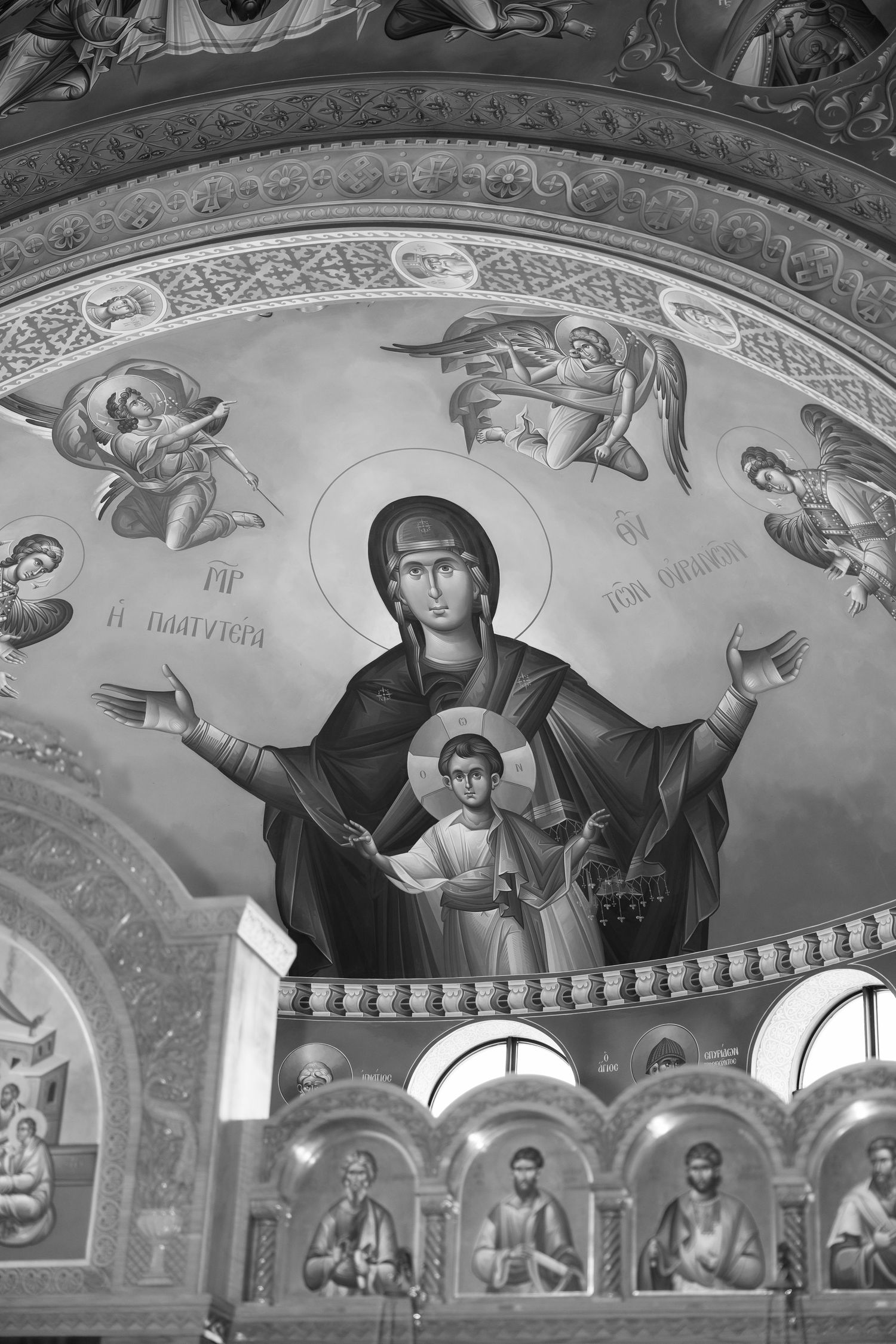 Religious fresco paintings on ornate church ceiling with decorative patterns.