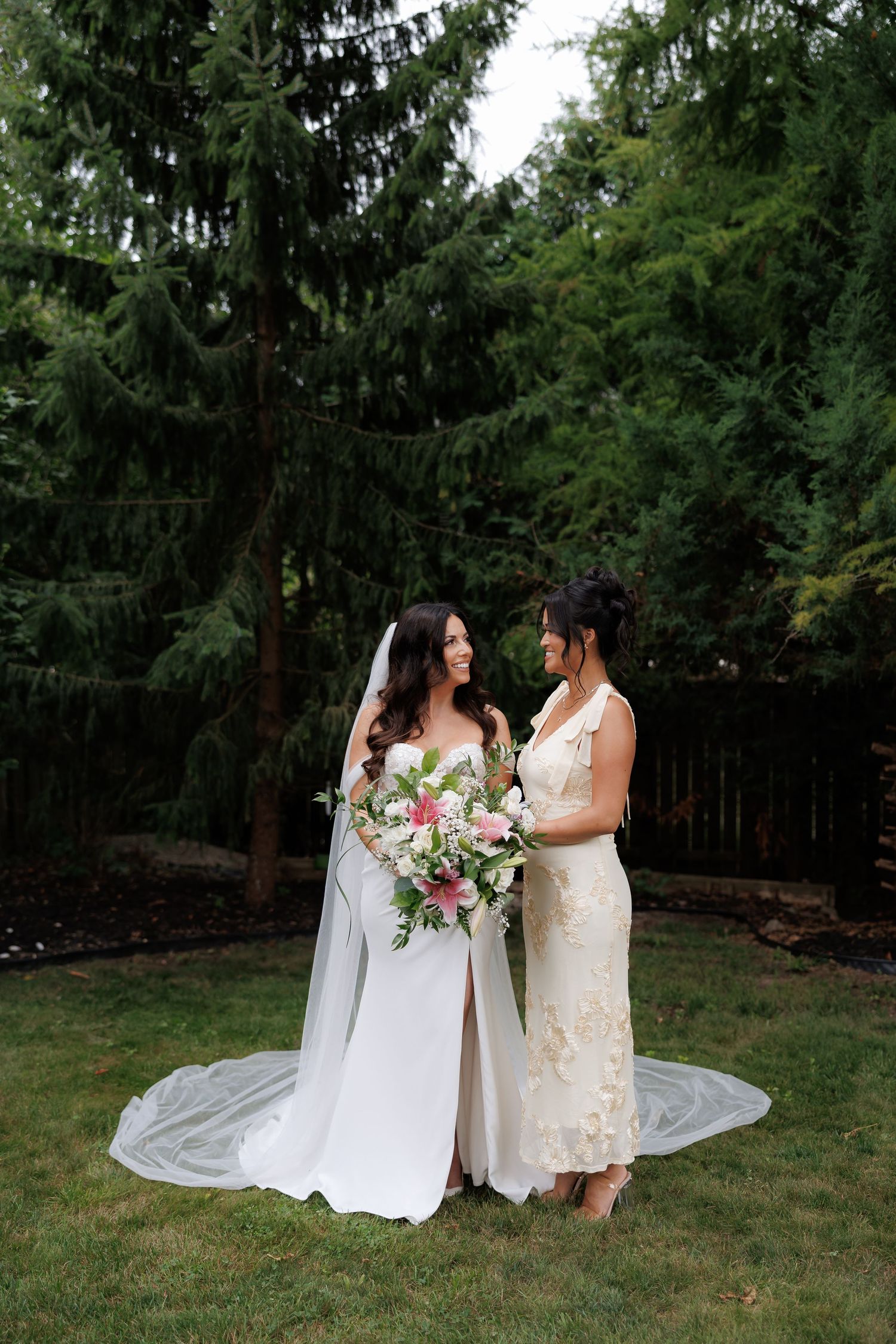 Two people in white dresses sharing a moment in a garden setting.