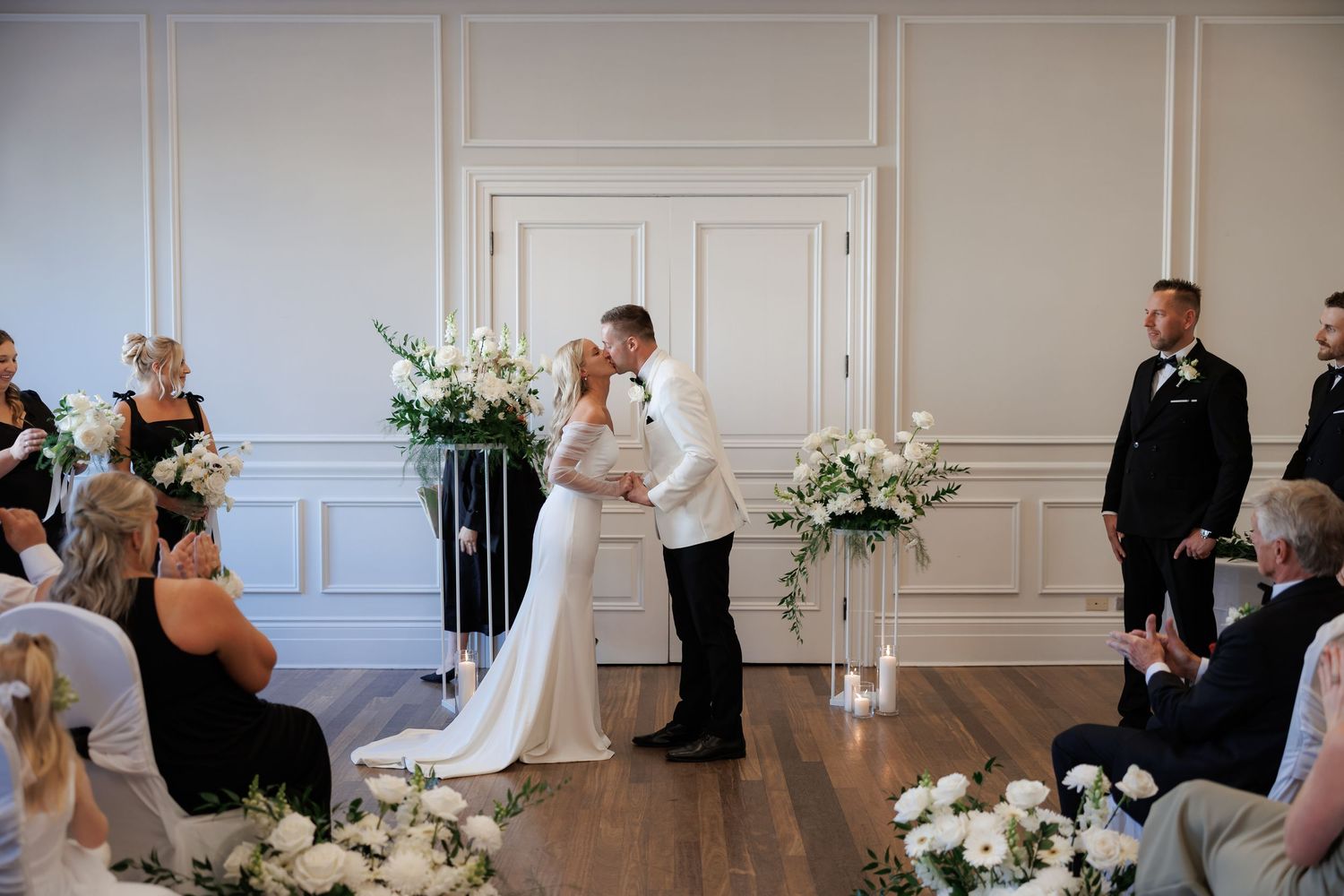 Elegant white ballroom with wainscoting serves as backdrop for wedding celebration.