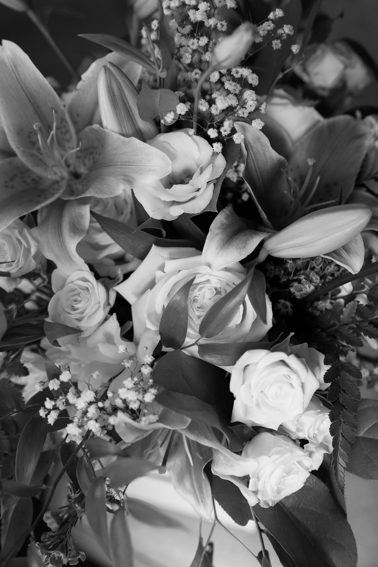 Elegant wedding bouquet with white lilies, roses and baby's breath arranged in black and white.