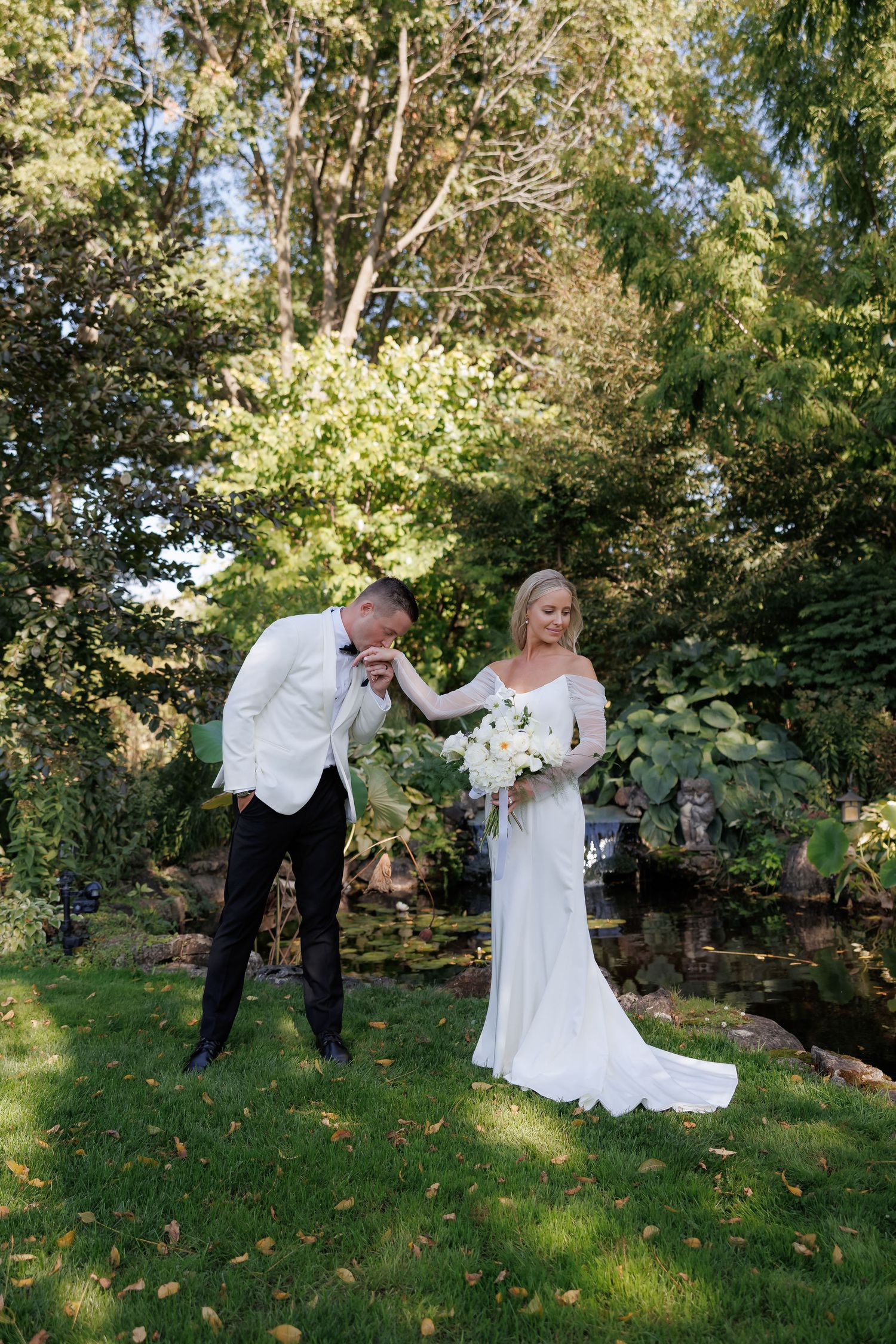 Playful wedding couple poses in garden setting with natural lighting.