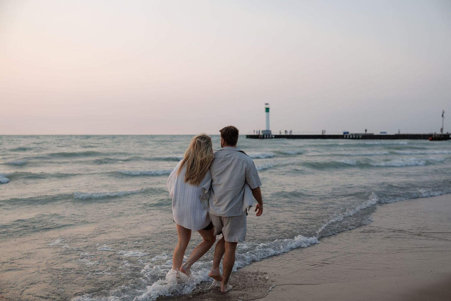 Romantic sunset photoshoot along a peaceful beach shoreline with soft pastel sky colors.