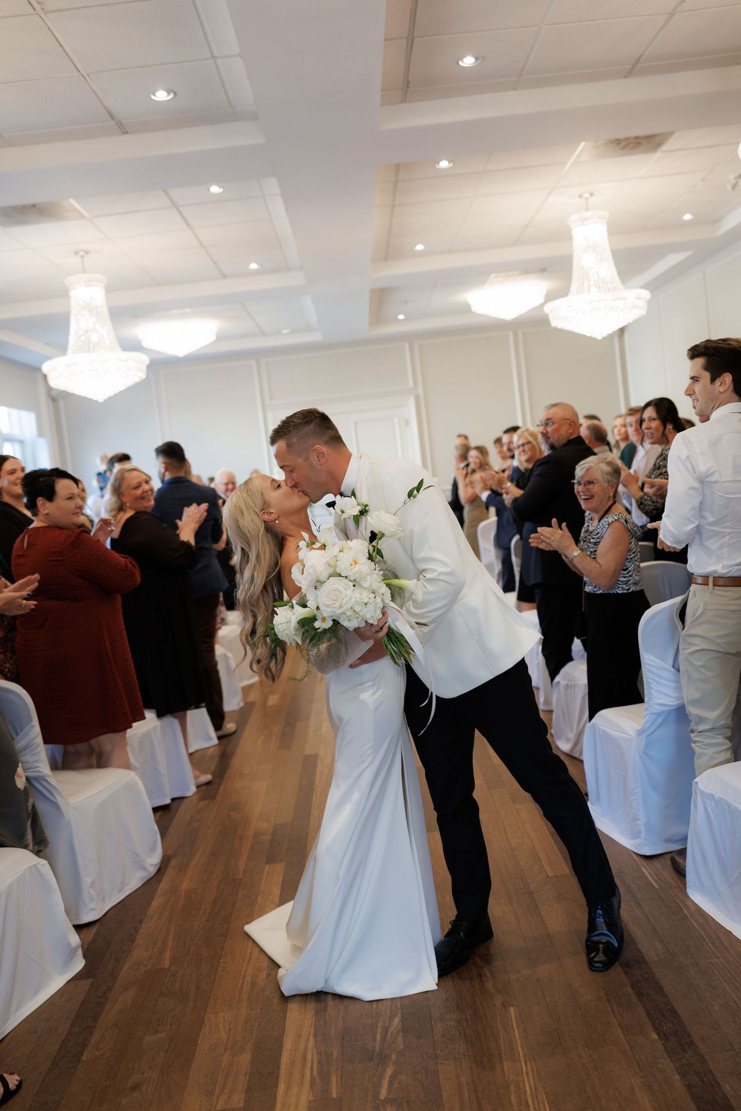 Wedding reception dance floor filled with couples dancing in an elegant white ballroom.