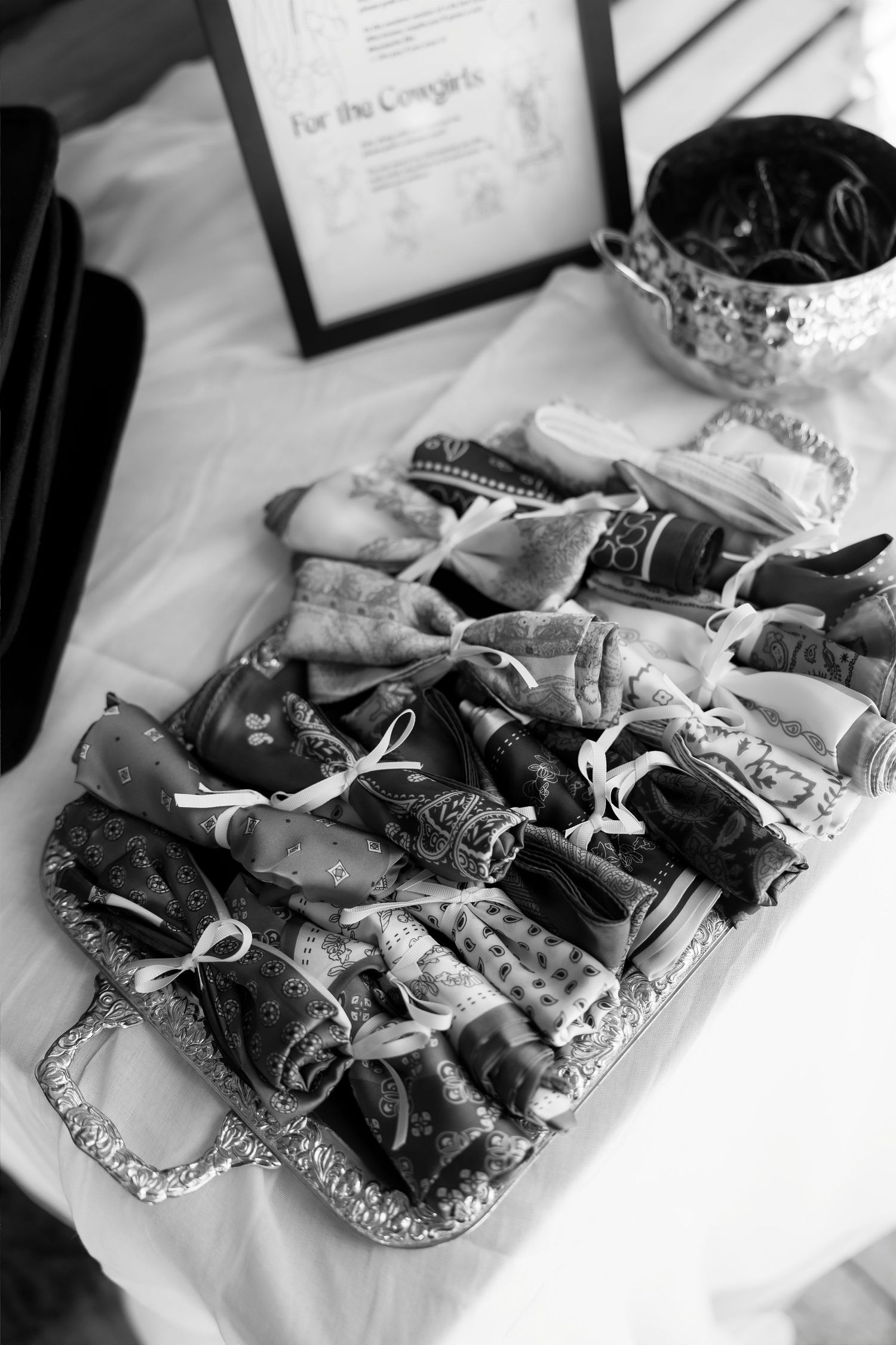 Rolled bandana favors tied with ribbon displayed on a silver tray at a rustic wedding reception.