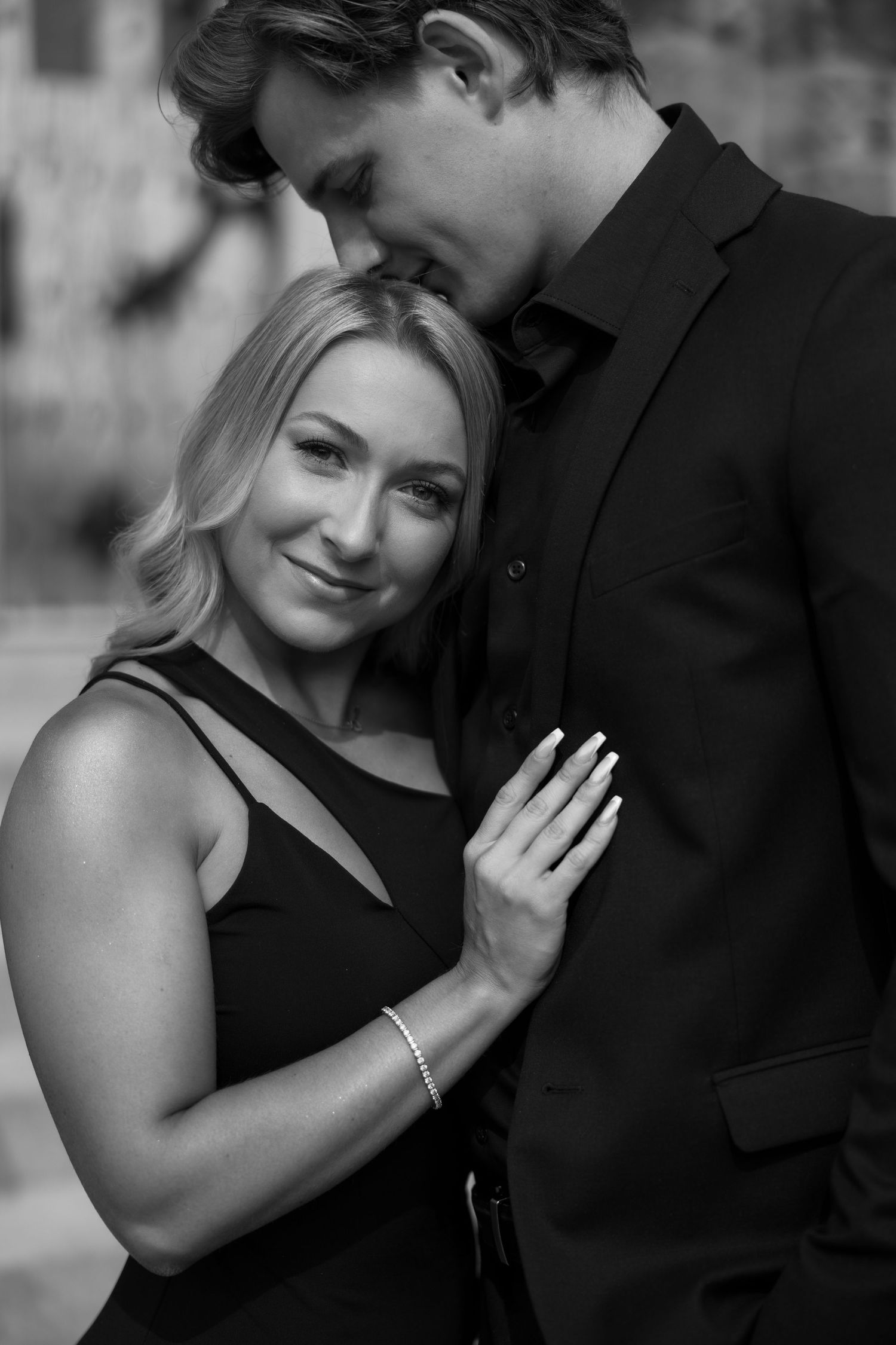 Black and white portrait of couple in formal attire sharing tender moment.