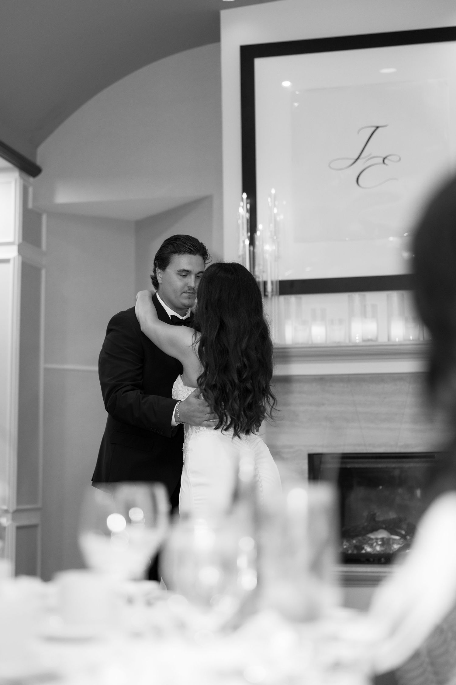 Black and white romantic moment captured through table settings at an elegant reception.