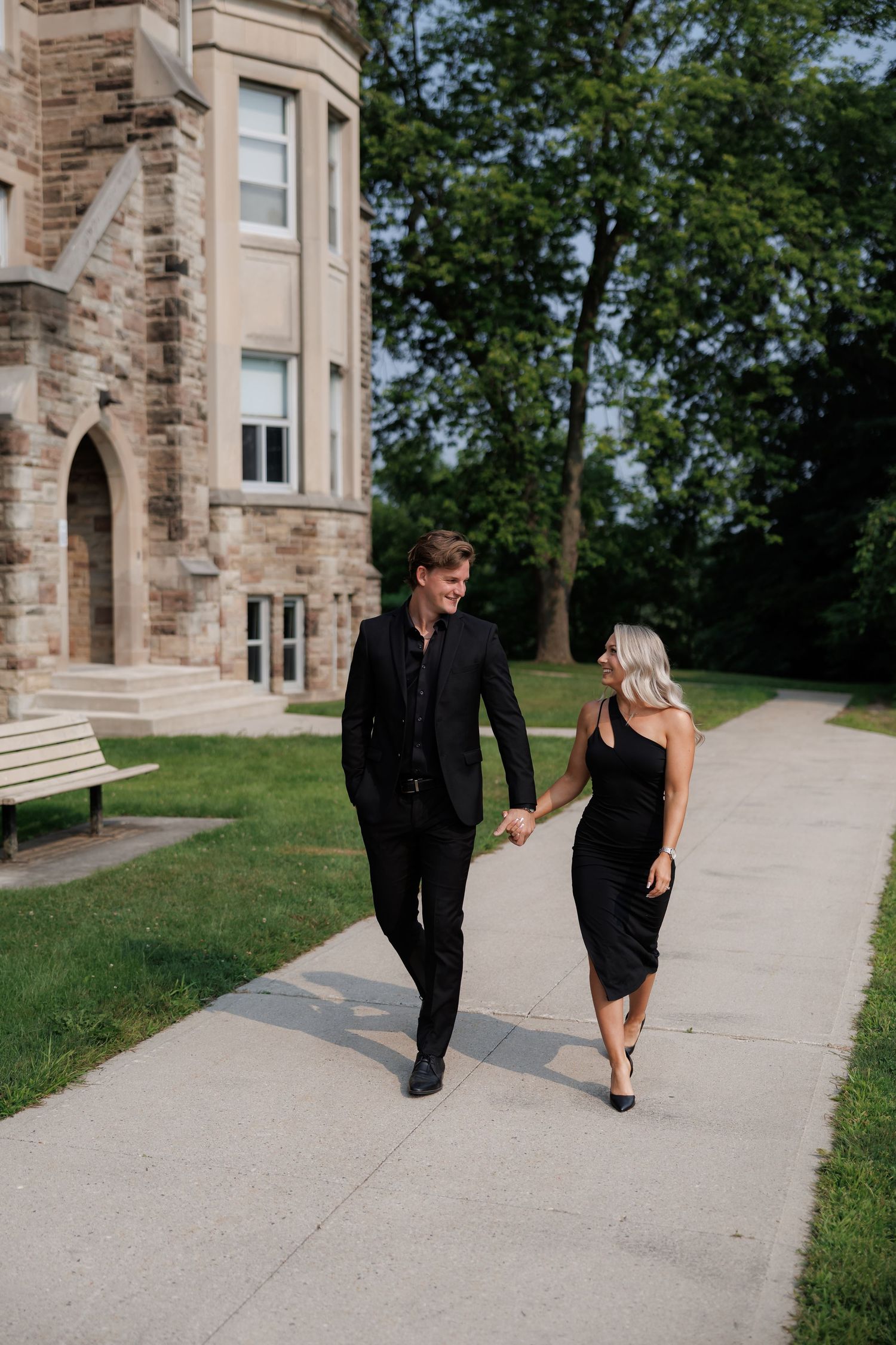 Couple walking along stone pathway outside historic building.