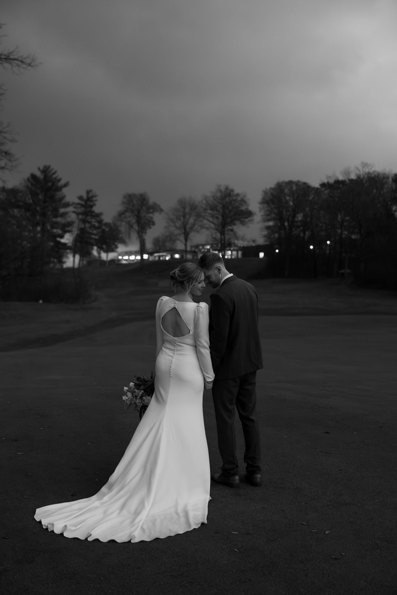 Black and white photos of a couple in wedding attire standing on a twilight golf course.