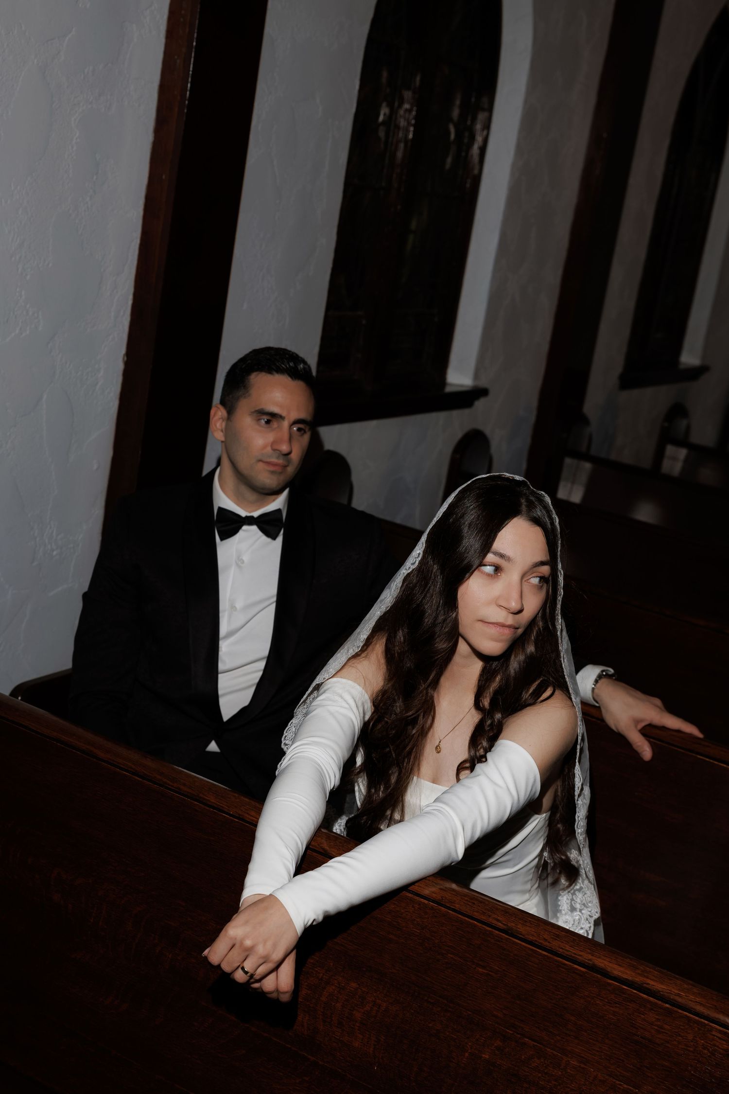 Artistic indoor wedding portraits with dramatic lighting in church pews.