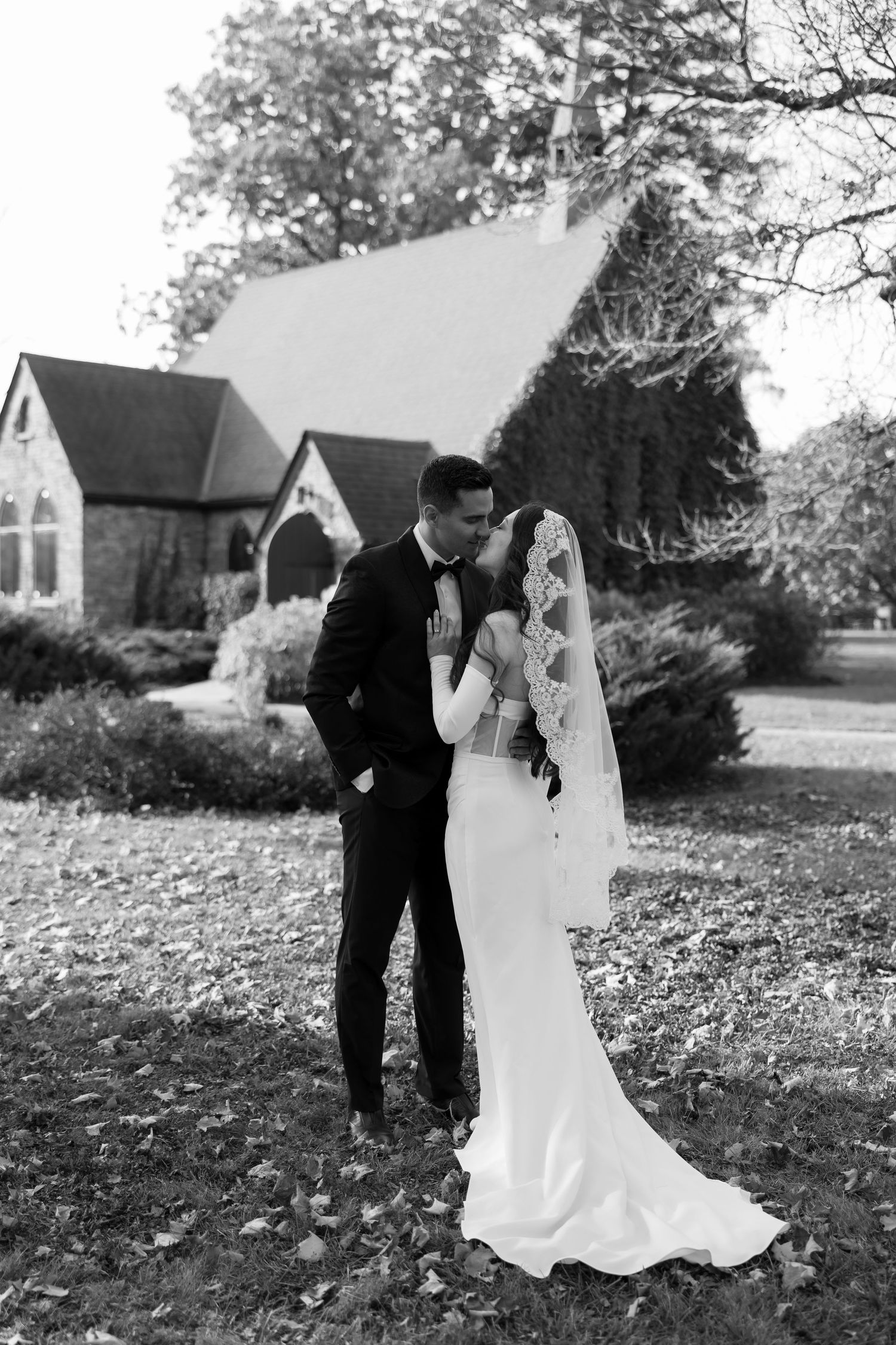 Black and white wedding portraits captured outdoors with a church building in the background.