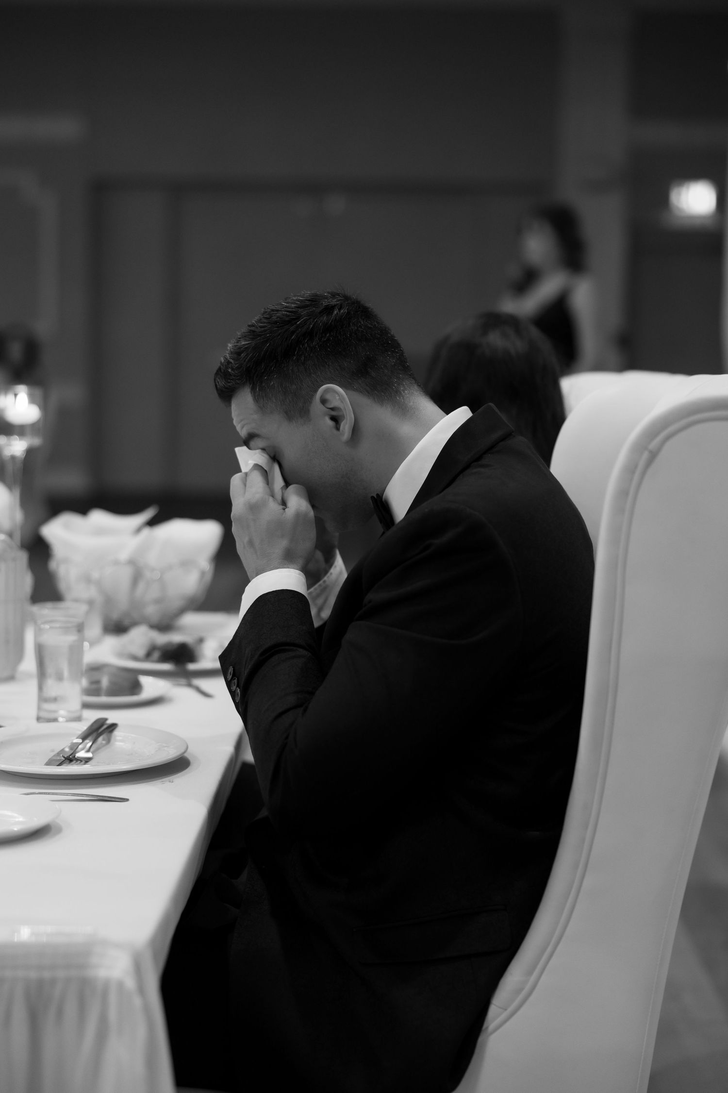 Black and white photo of emotional moment during wedding reception dinner.