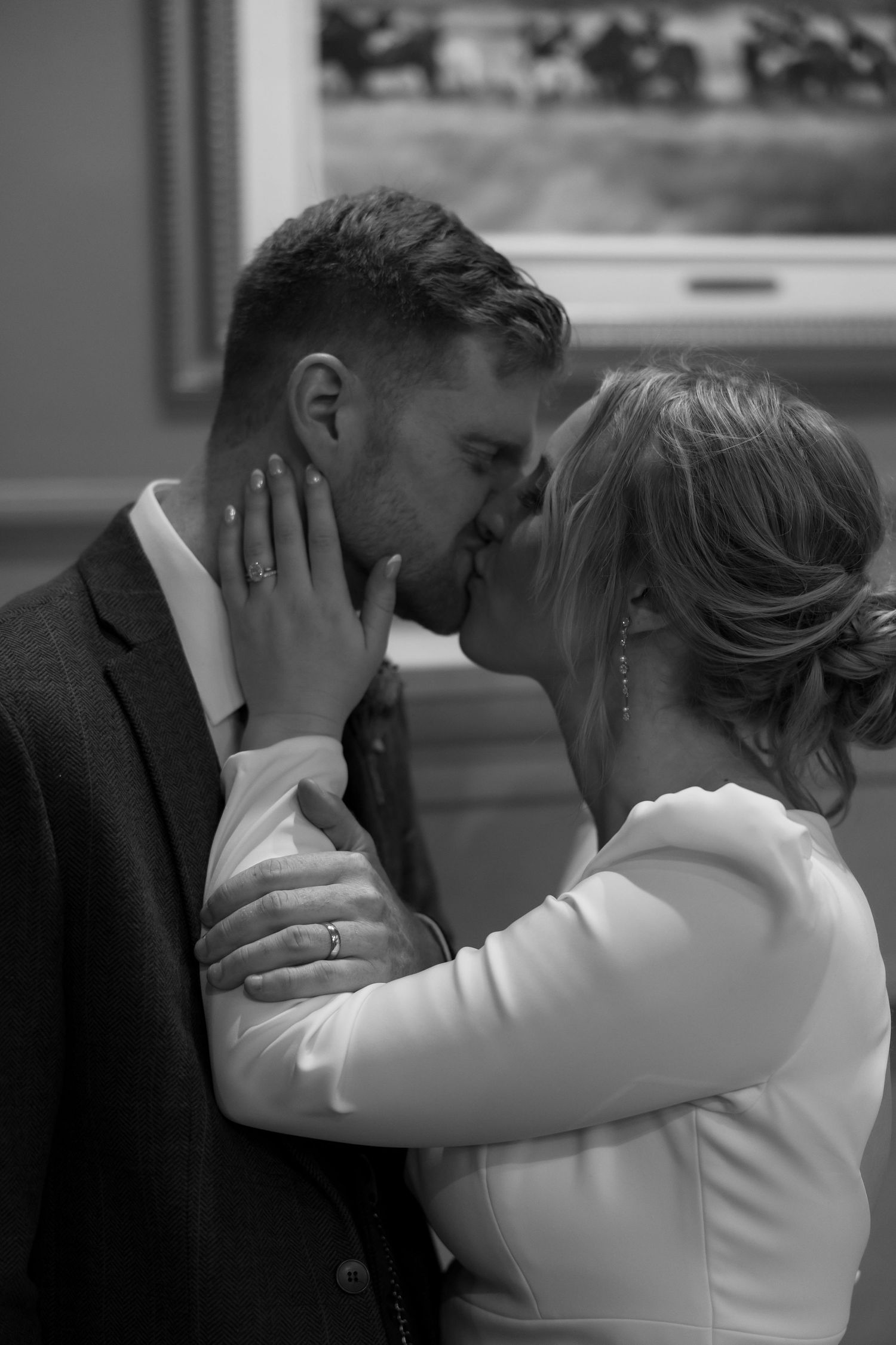 A romantic black and white photo series showing a couple embracing and kissing in an intimate moment.