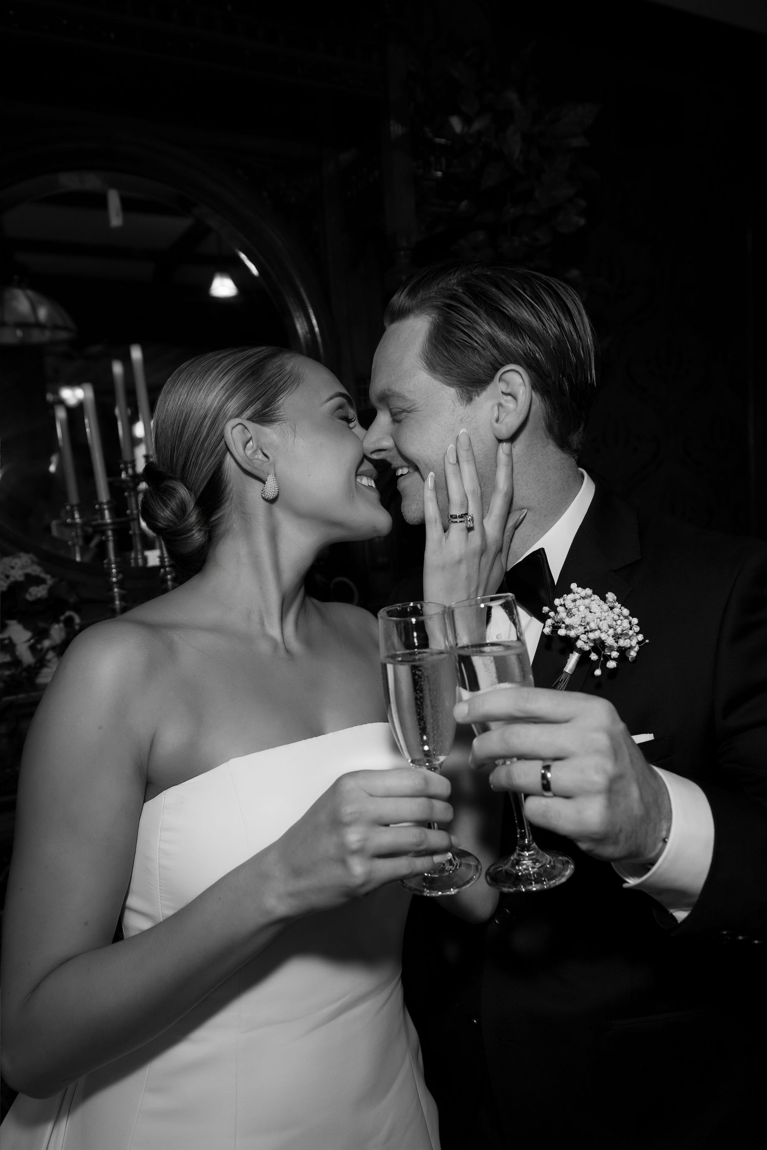 Bride and groom toasting with champagne flutes, sharing a romantic moment in black and white wedding photography.