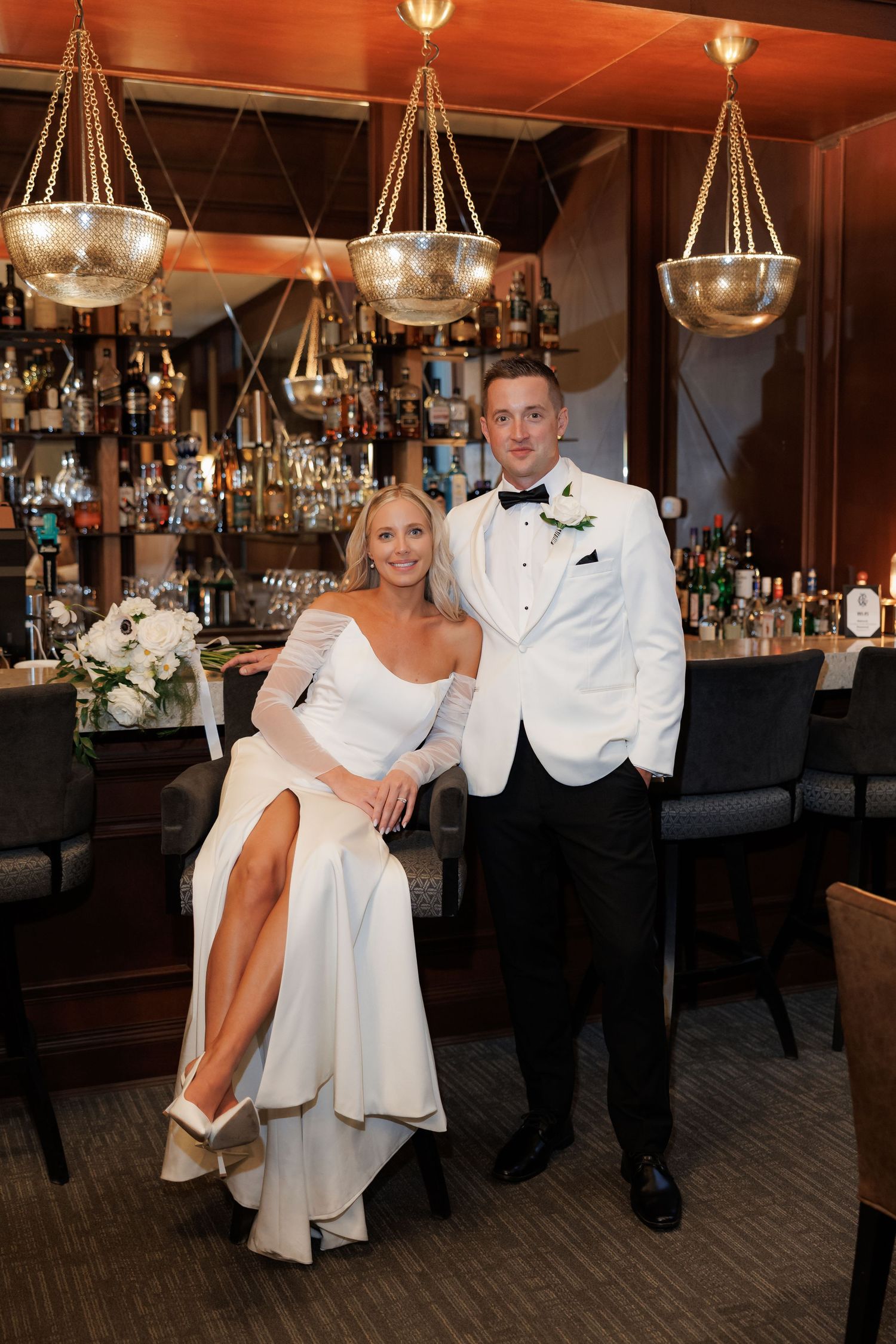 Stylish bar setting with hanging lights serves as backdrop for wedding photos.