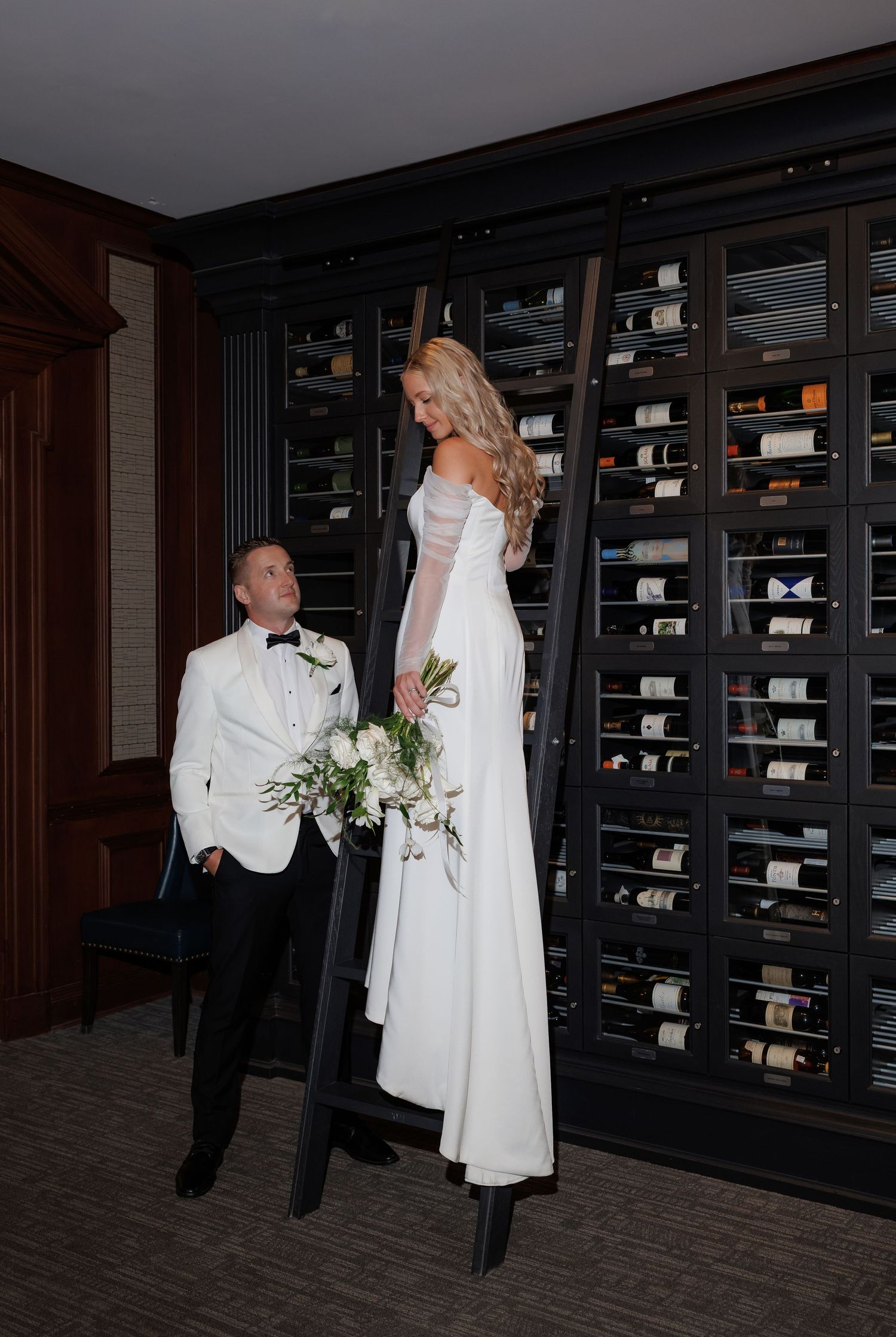 Couple shares intimate moments in a room with dark wood built-in bookshelves.