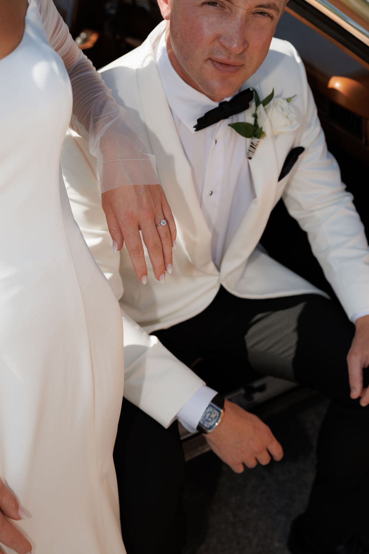 Close-up details of formal white tuxedo attire and accessories.