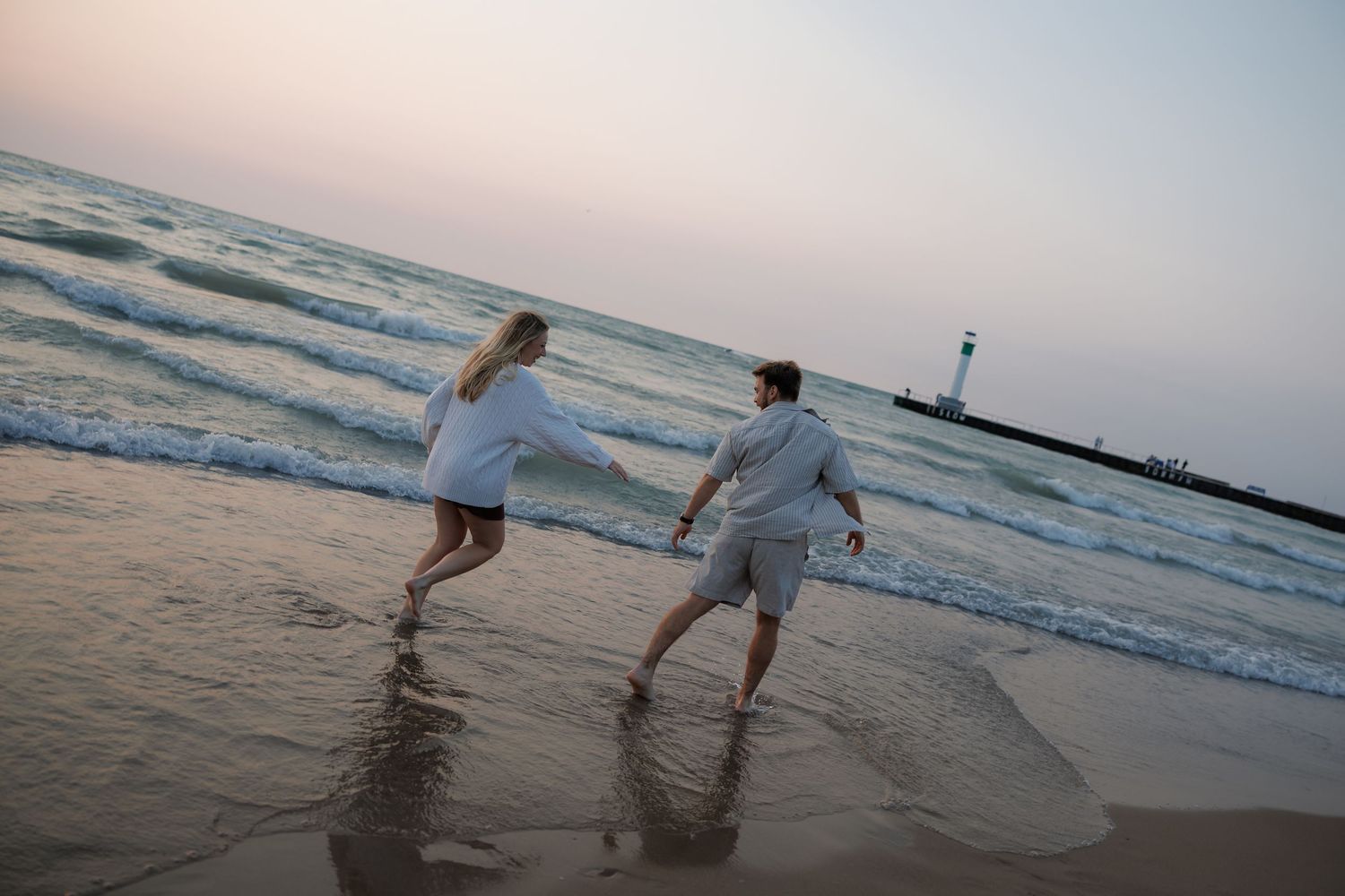 Couple walking along the shoreline during golden hour at the beach.