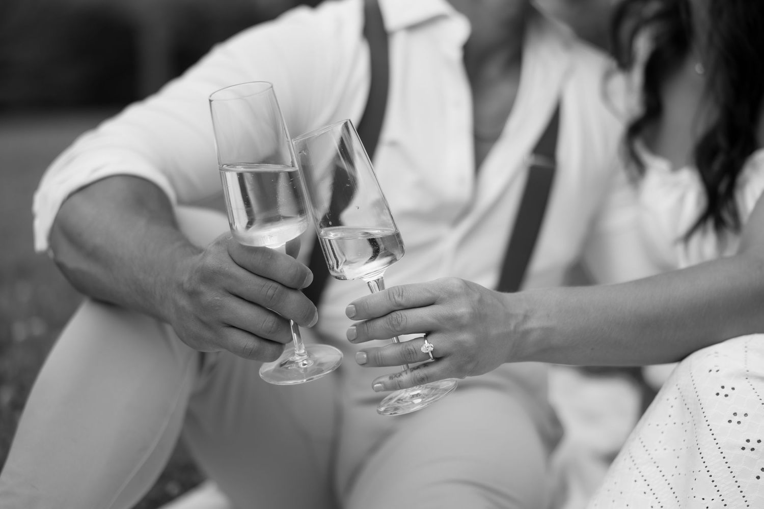 Two champagne glasses clink together in an elegant black and white celebration moment.