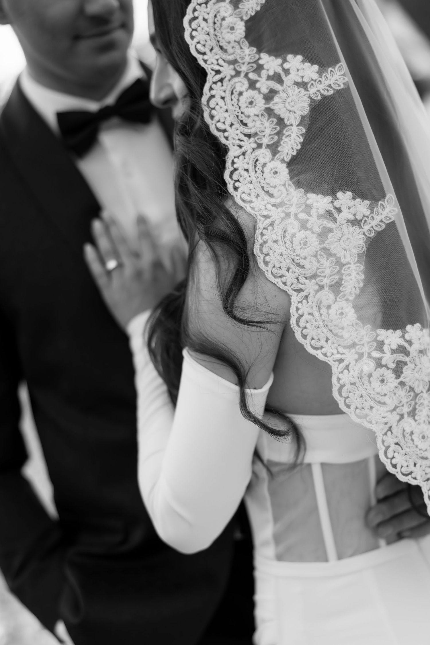 Close-up details of delicate lace wedding veil and dress in black and white.