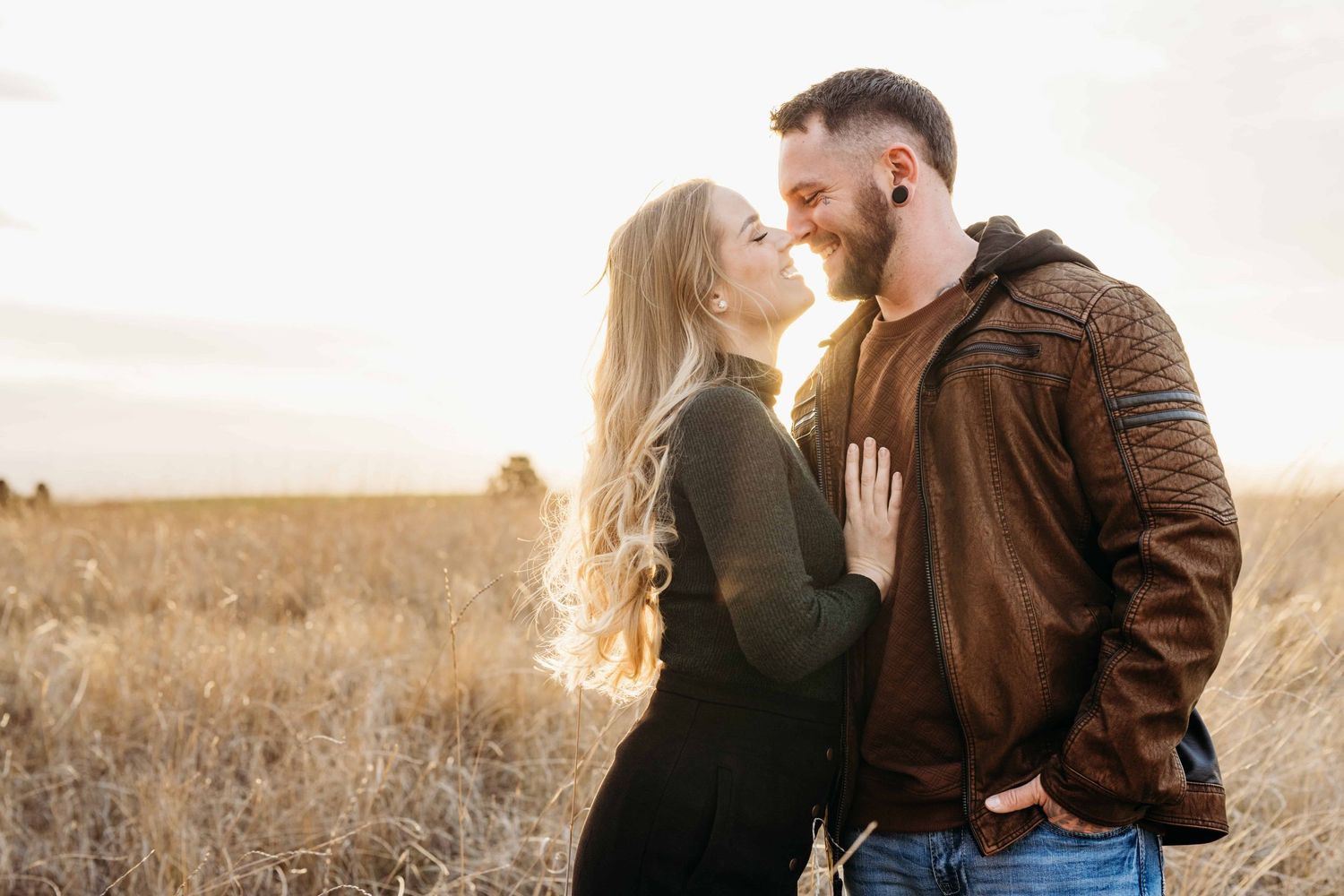 A couple standing with their noses touching in an intimate golden filled portrait.