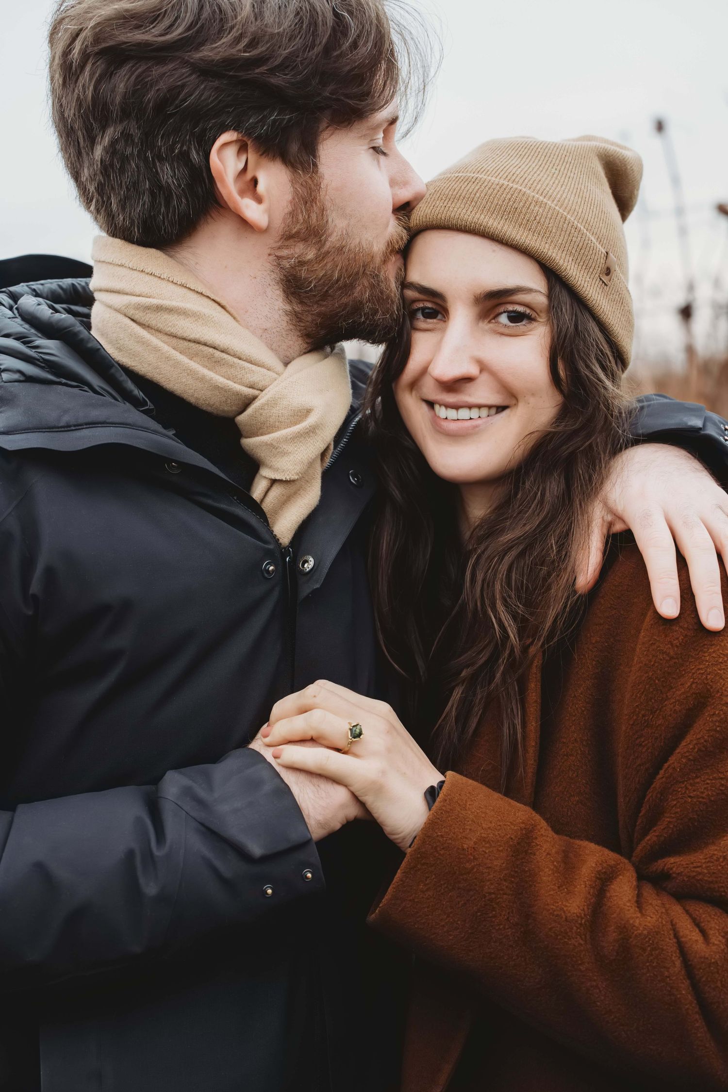 A man kissing his new fiancee just after proposing at a vineyard.