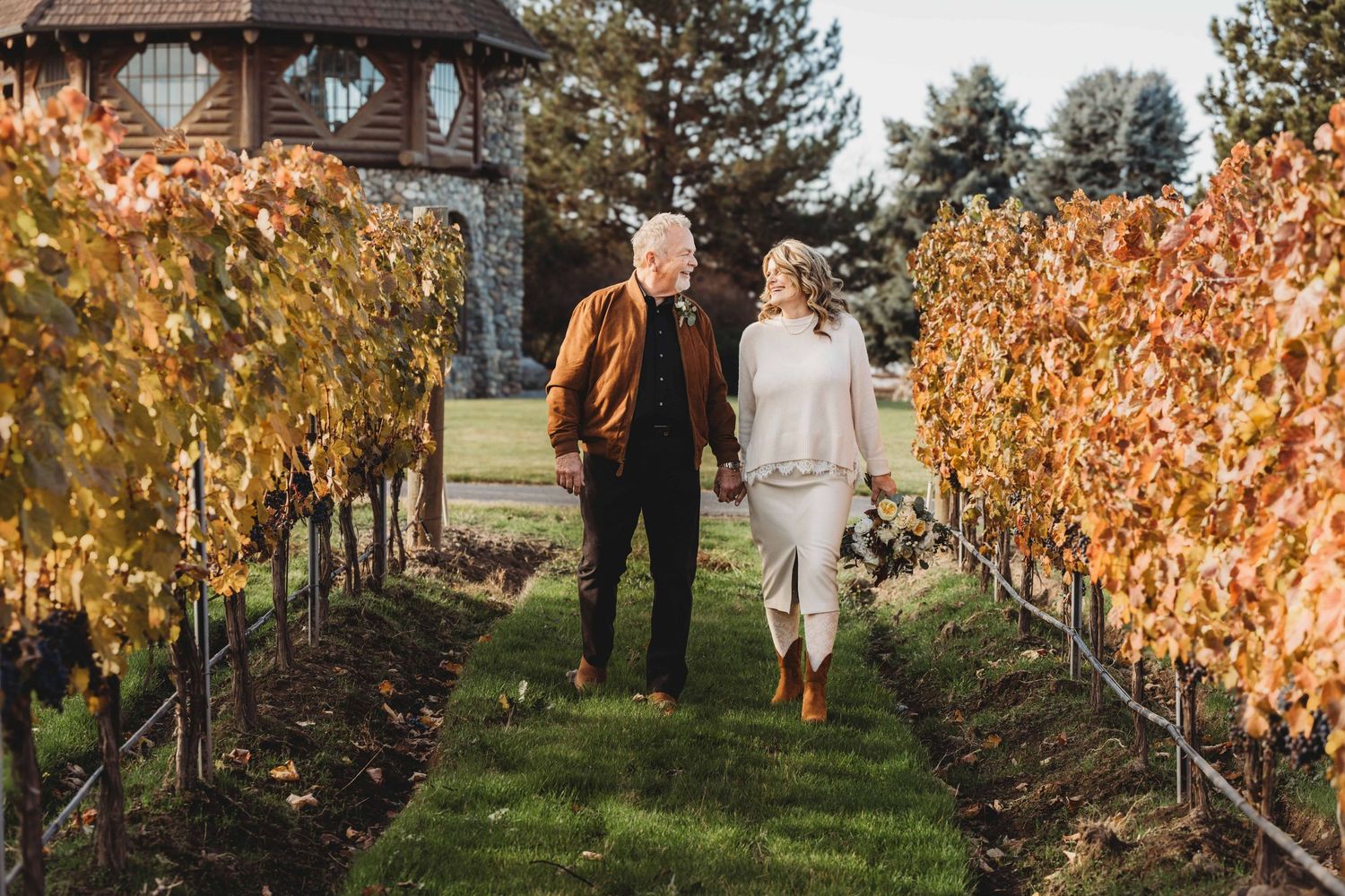 Bride and groom walking through a vineyard in the fall after their wedding ceremony.