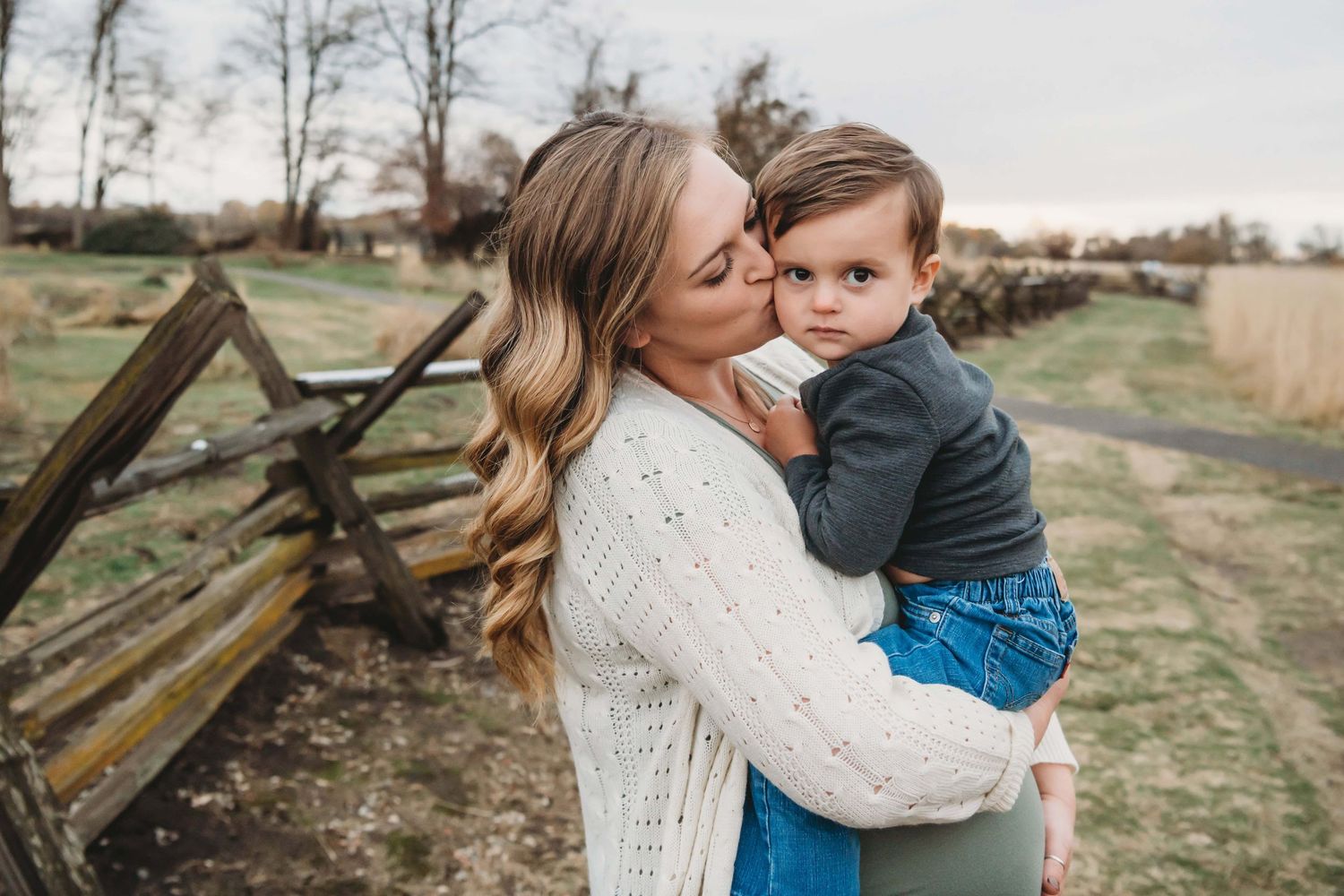 Mother holding her toddler during a family photography session in Walla Walla, captured in a natural outdoor setting.