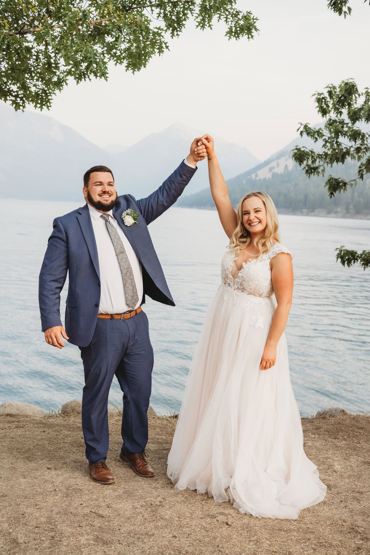 A couple holding their hands up after their elopement ceremony at Wallowa Lake.