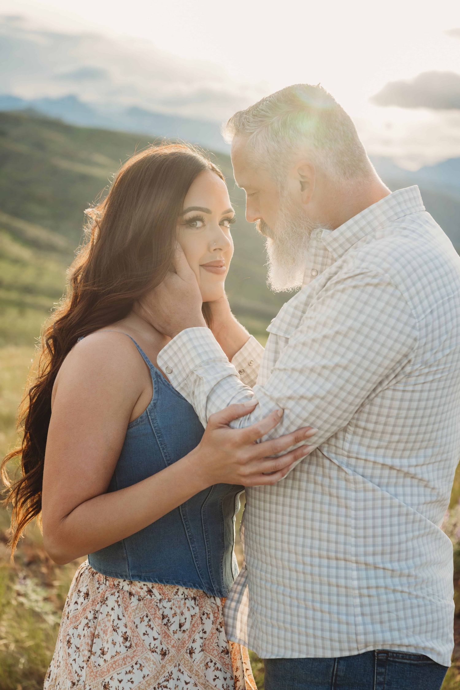 A portrait of a husband looking at his wife with sunshine and mountains in the background.