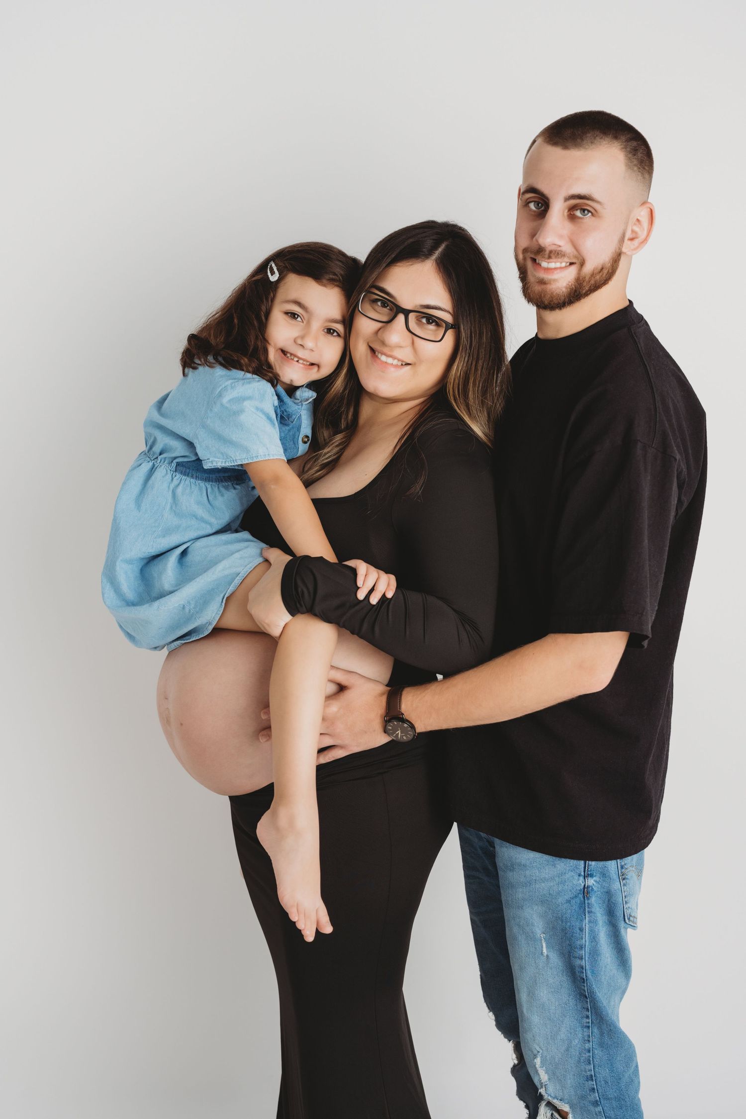 A family studio portrait of a pregnant mother with her husband and young daughter in Walla Walla.