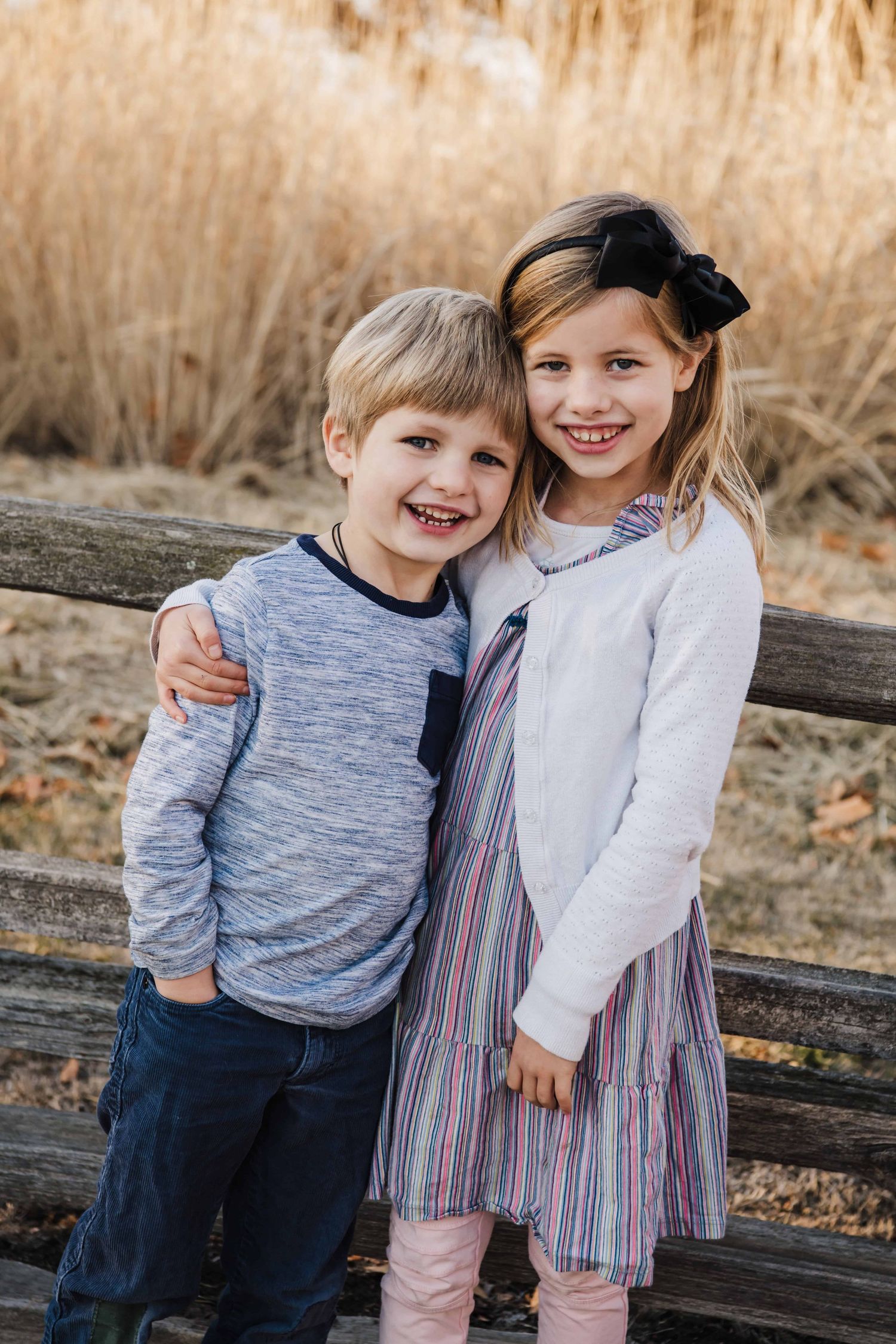 Two children with their arms around each other smiling in front of a fence at Whitman Mission in Walla Walla.