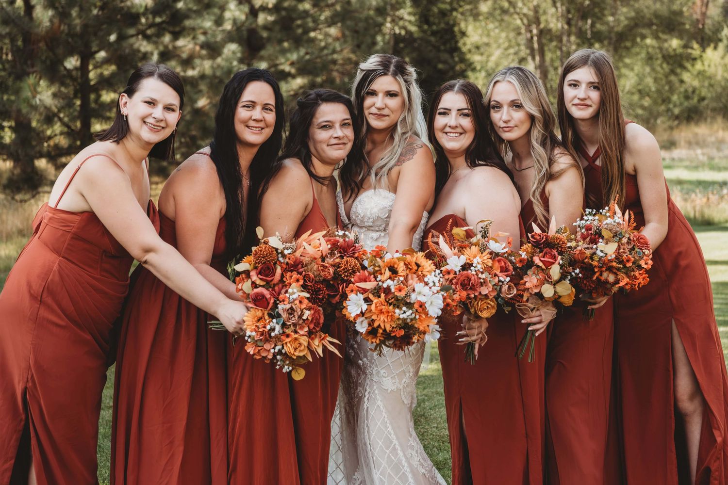 A group of bridesmaids in rust colored dresses surrounding the bride on her wedding day.