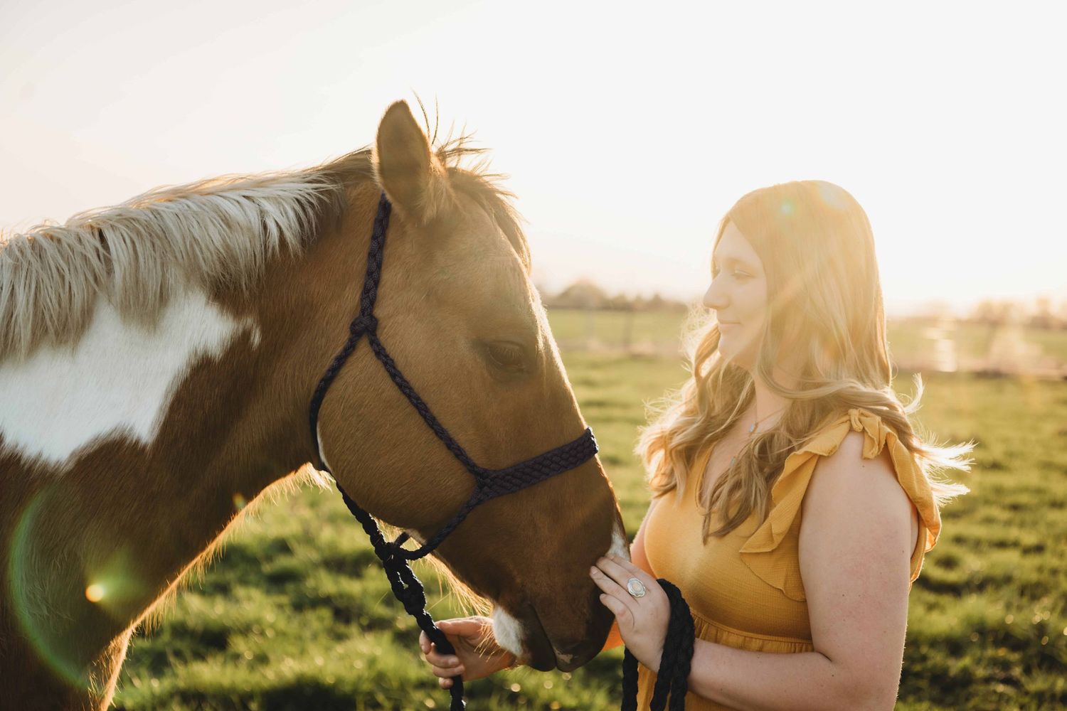 A candid portrait of a girl looking at her horse and smiling during a senior session in Walla Walla.