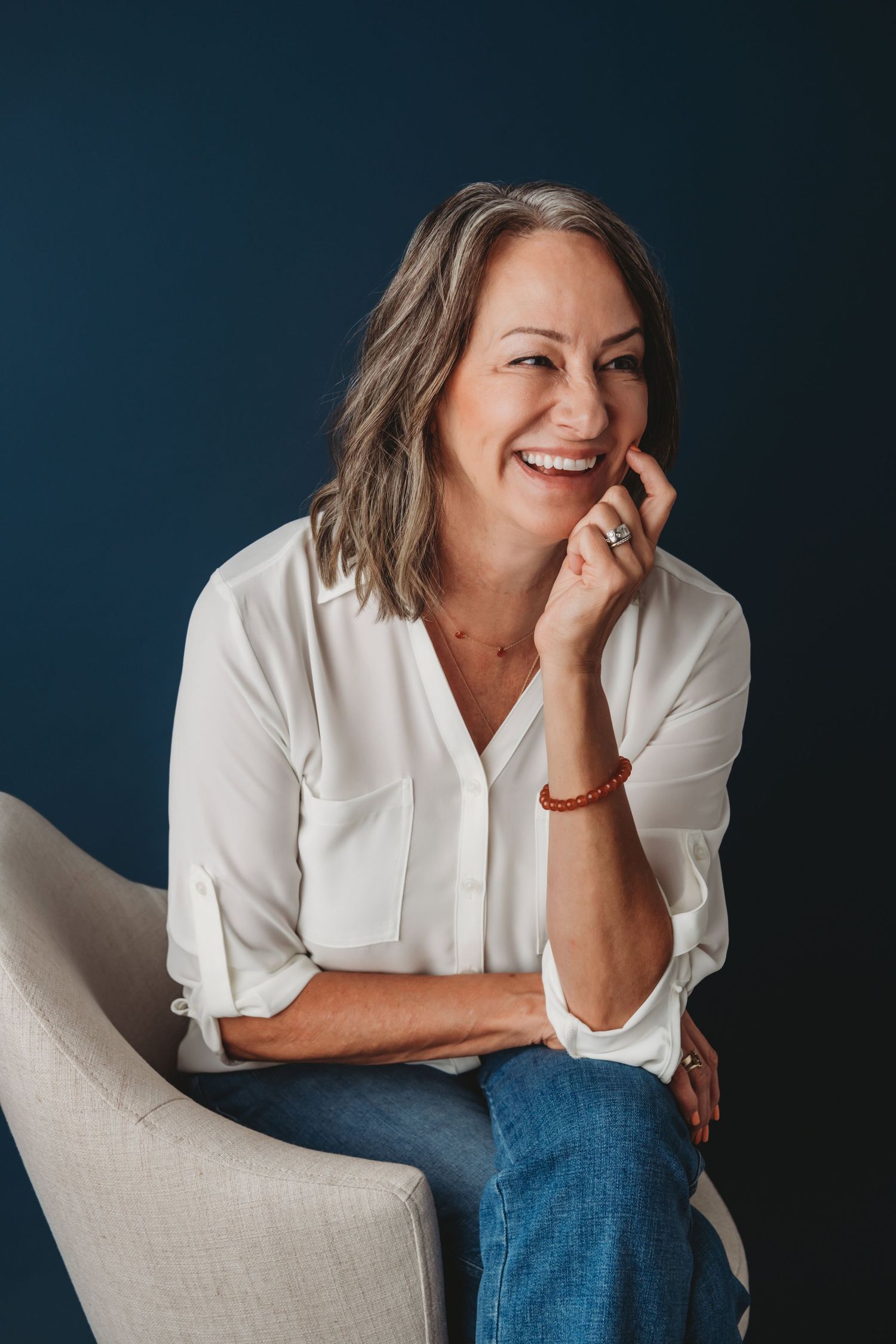 A Walla Walla headshot photographer captures a candid moment of a woman sitting in a chair and laughing.