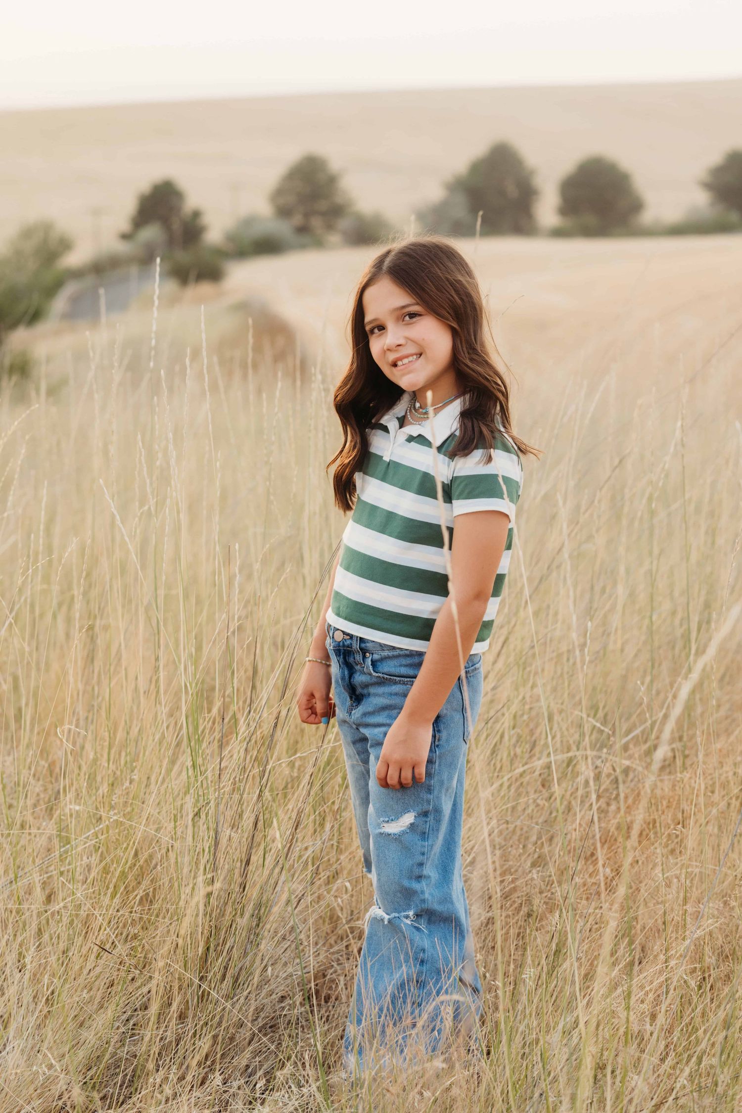 A classic portrait of a child in jeans and a t shirt smiling at the camera.
