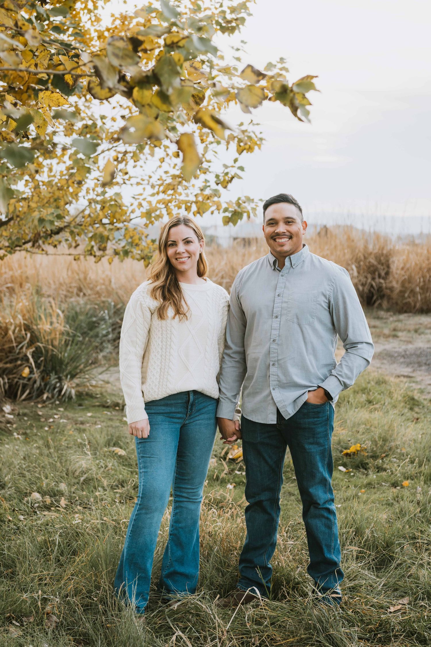 A couple standing under a tree on a fall day in Walla Walla.