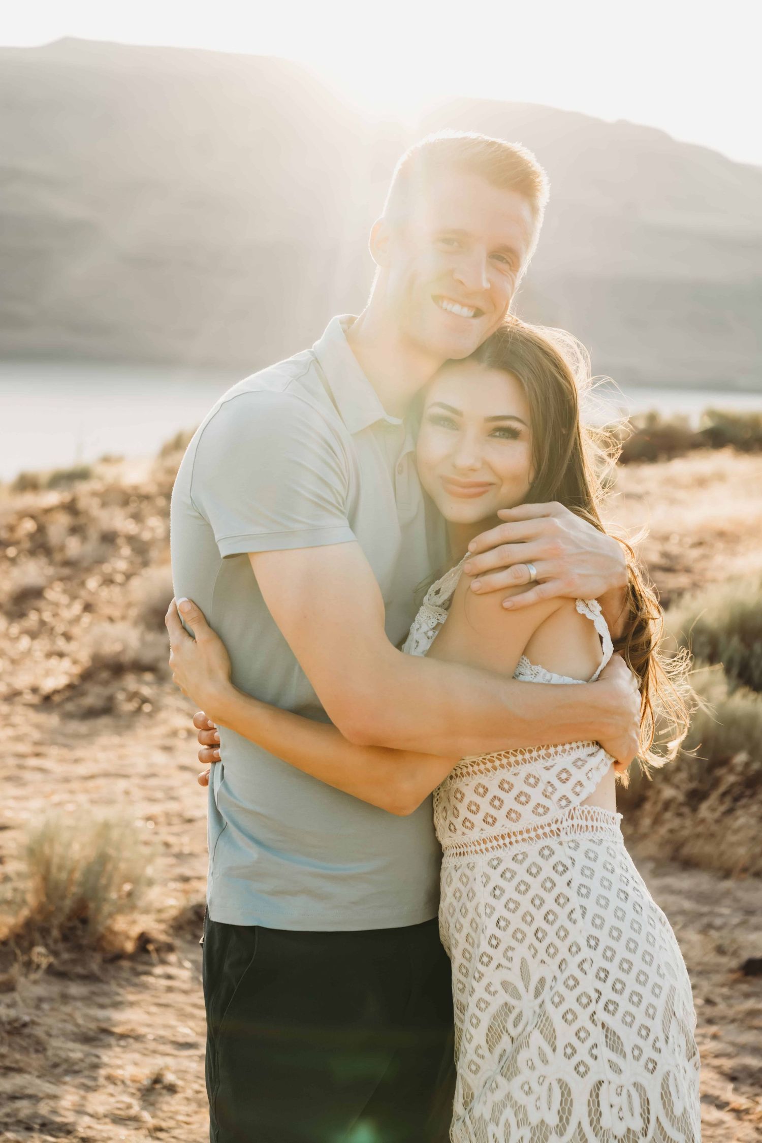 A couple hugs during golden hour with soft sun rays covering them, captured by a Walla Walla photographer.