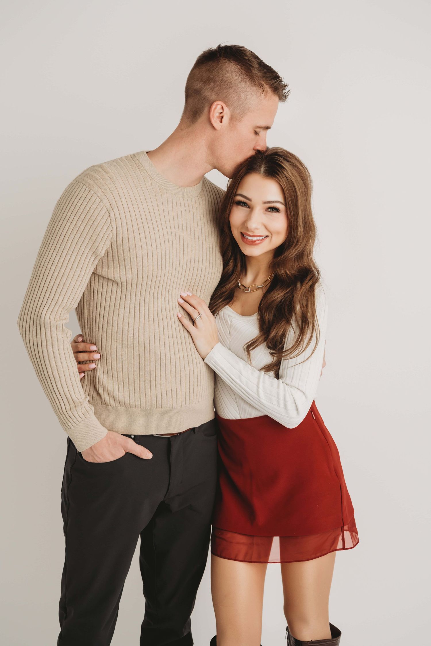 Couple embracing while a man kisses his wife on the head in a studio couples photography session in Walla Walla