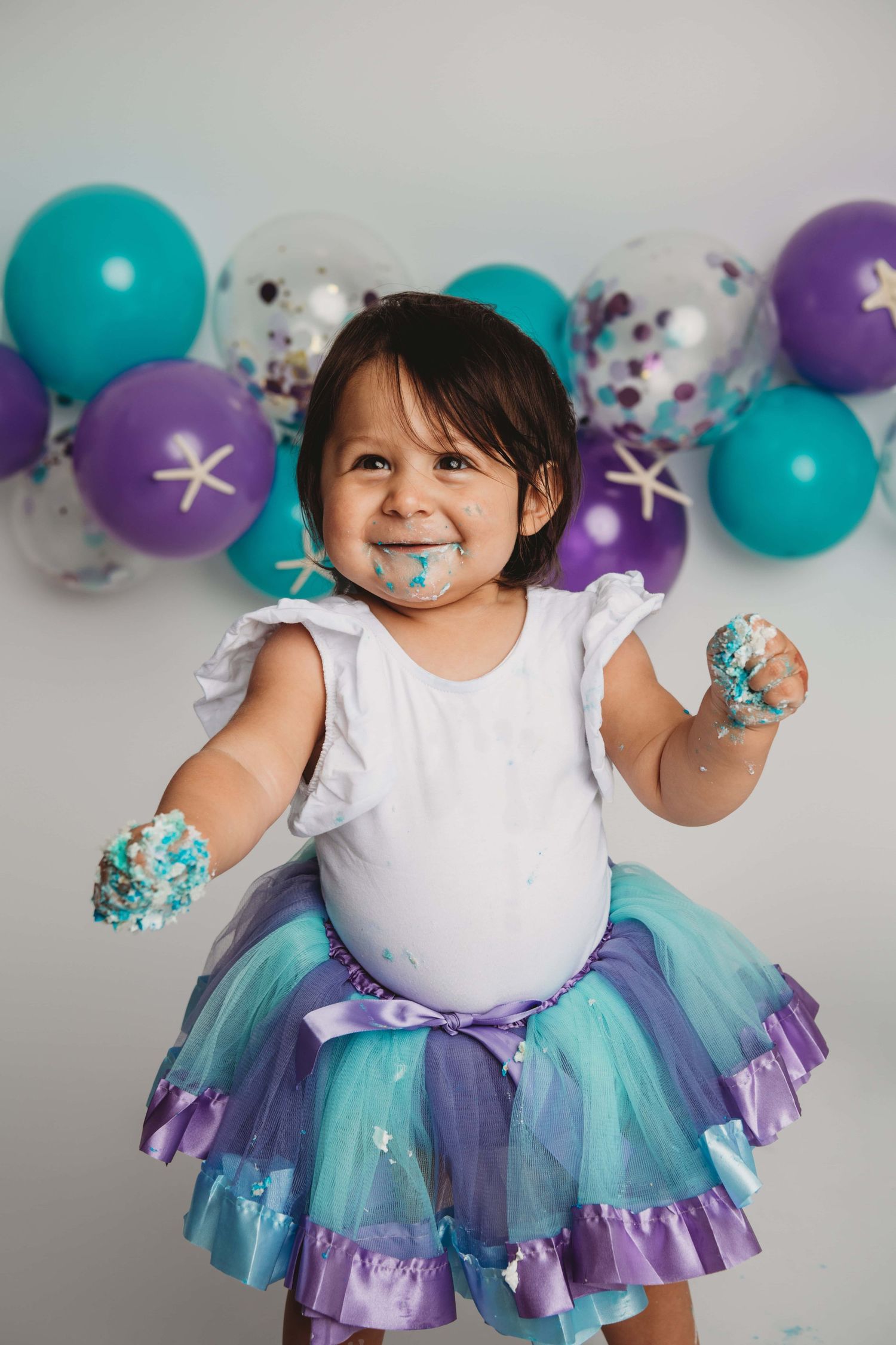 A portrait of a one year old with a mermaid themed outfit and background.