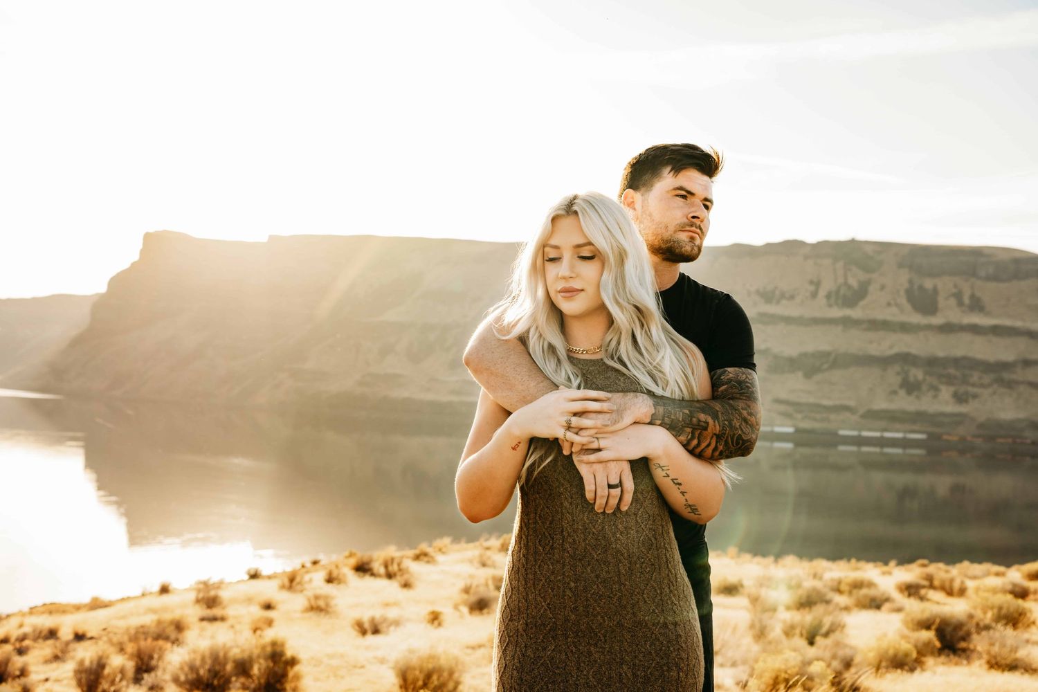 Golden hour portrait of a couple embracing, captured by a Walla Walla photographer as they look off into the distance.