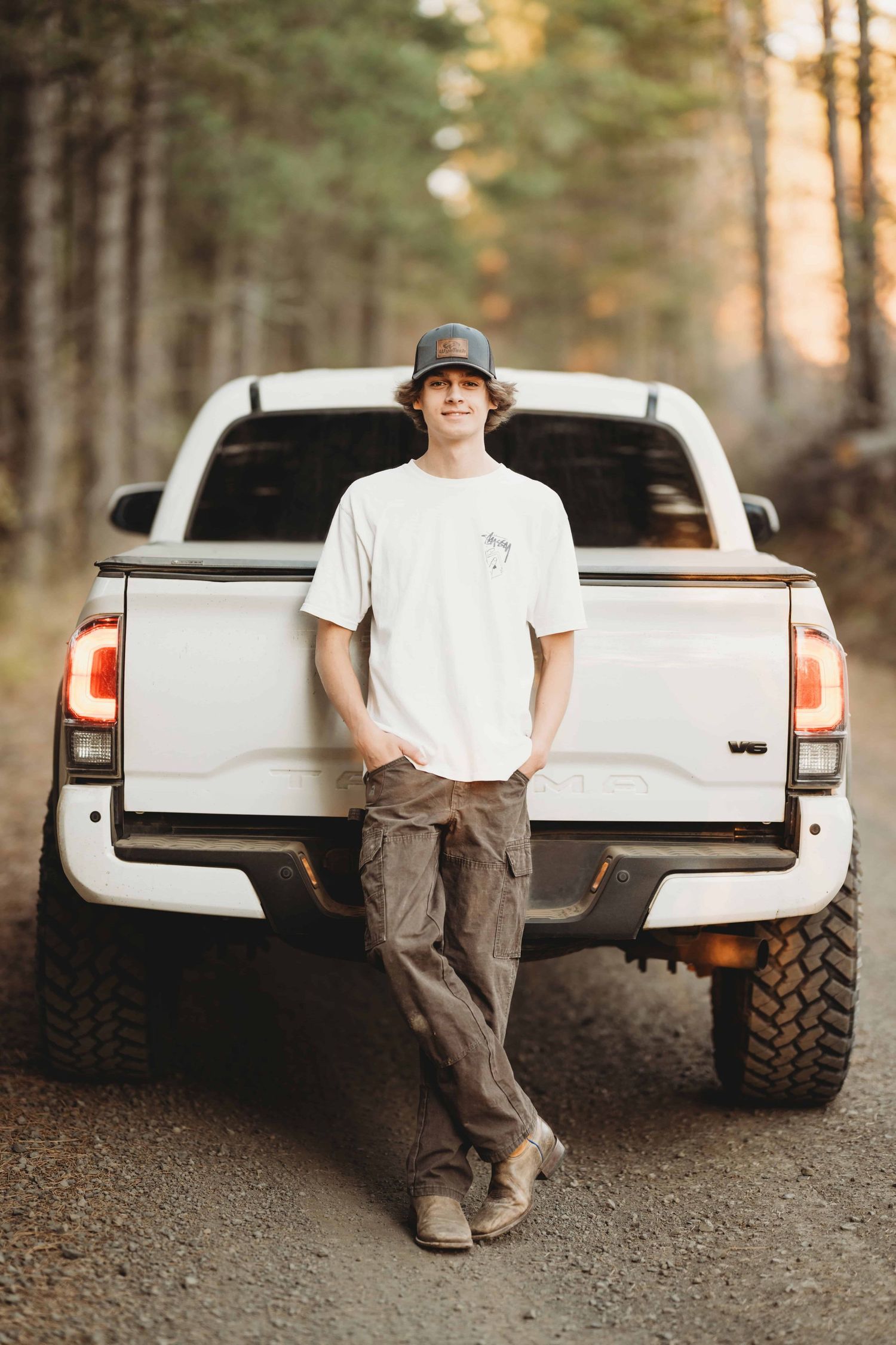 A Walla Walla senior photographer captures a young man standing in front of his white truck with his legs crossed.