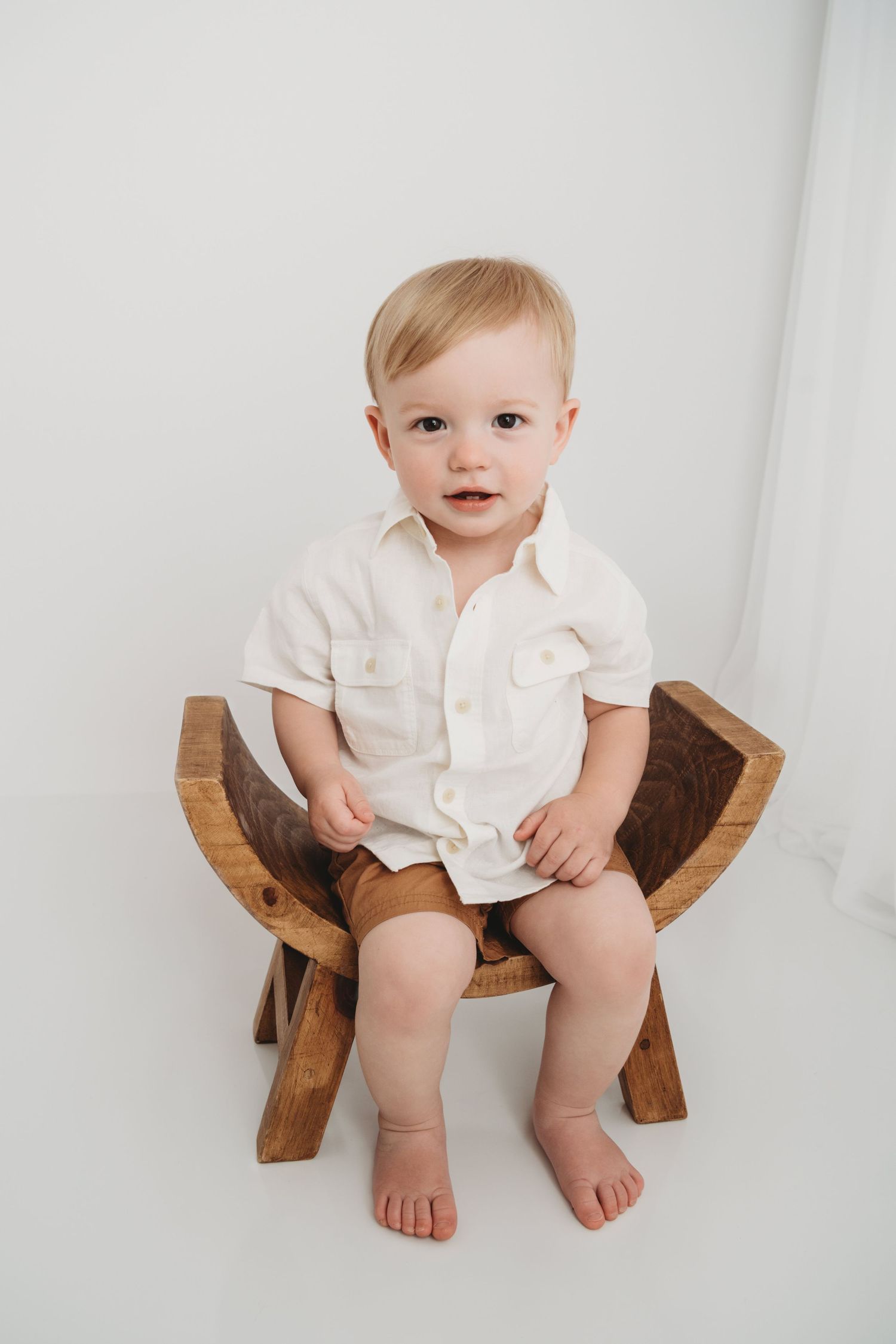 A two year old boy sitting on a wooden bench at a Walla Walla portrait studio.