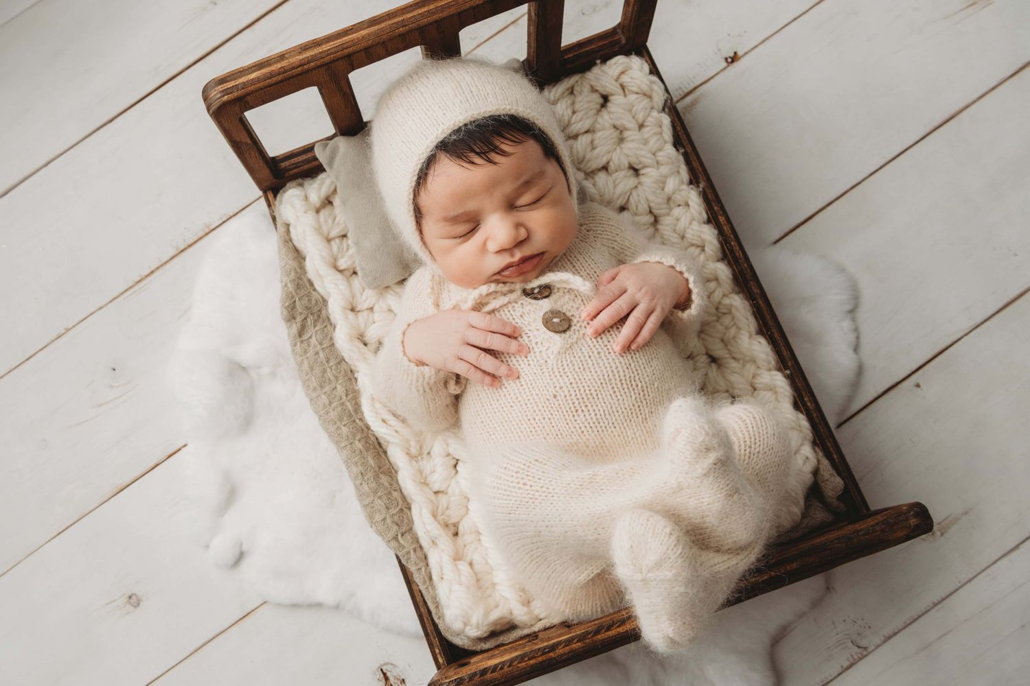 Baby boy in neutral tones sleeping on a bed in a Kennewick newborn photography studio.