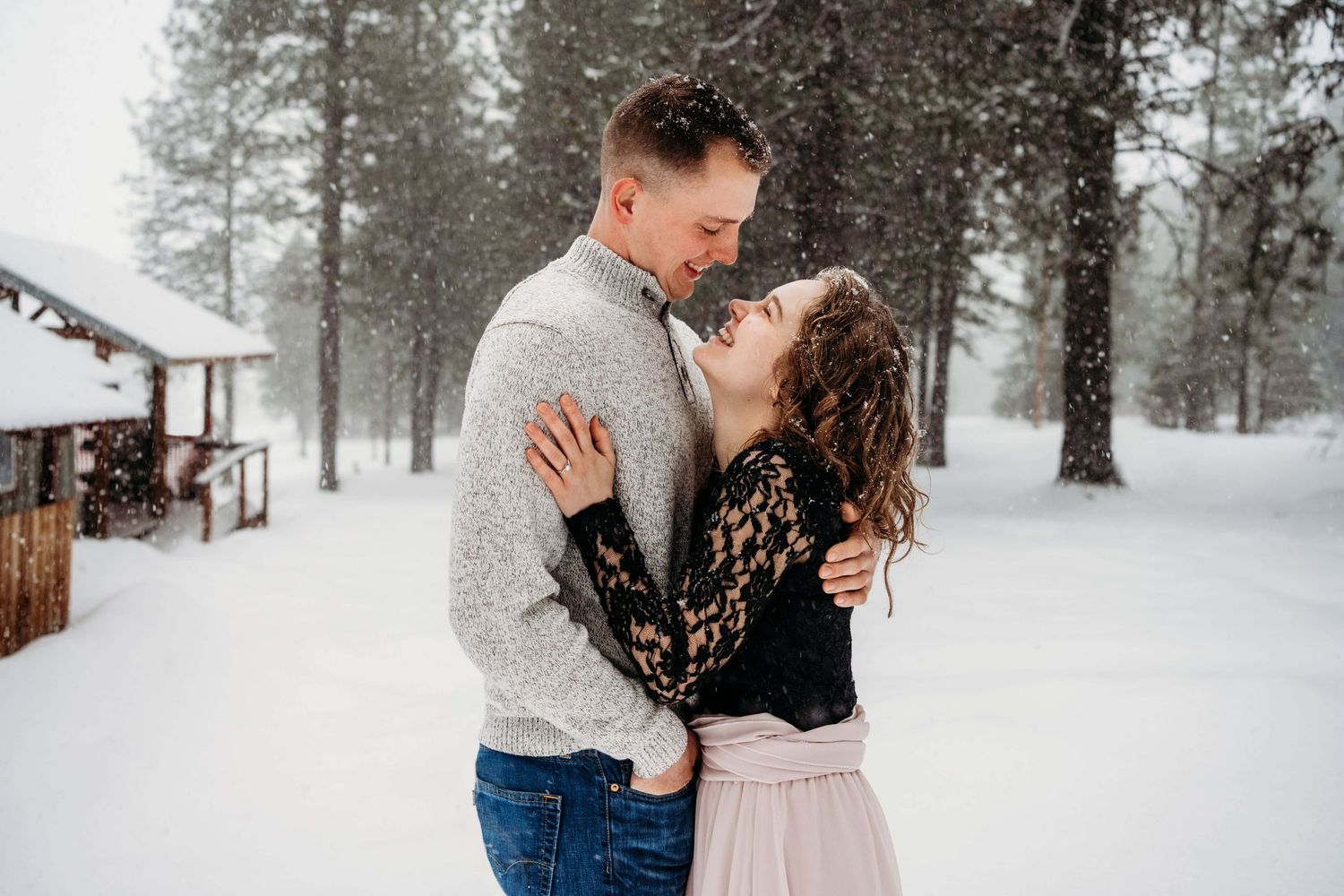 A couple playfully embracing and laughing together in the snow.